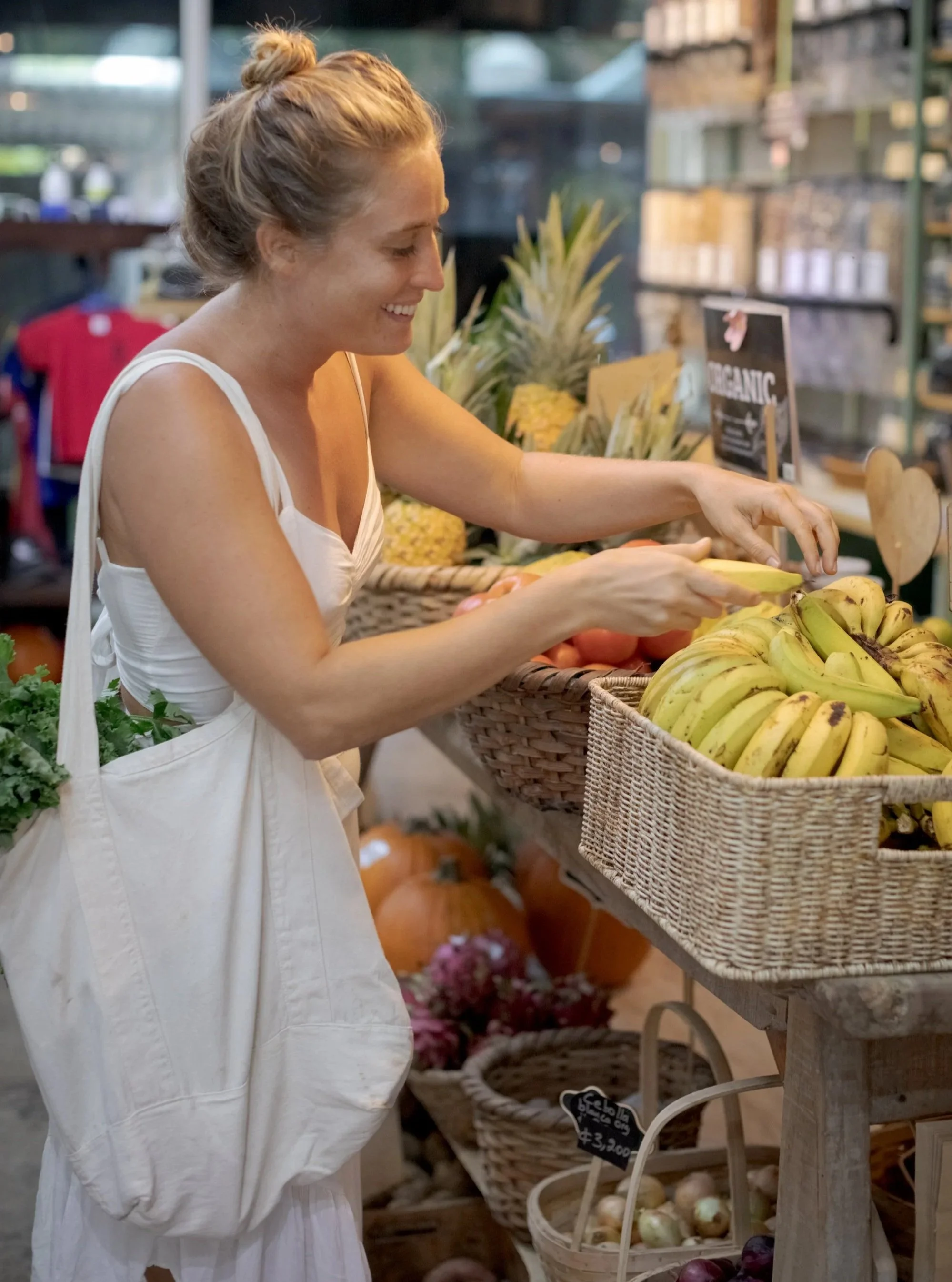 A woman shopping for bananas at a farmer's market.