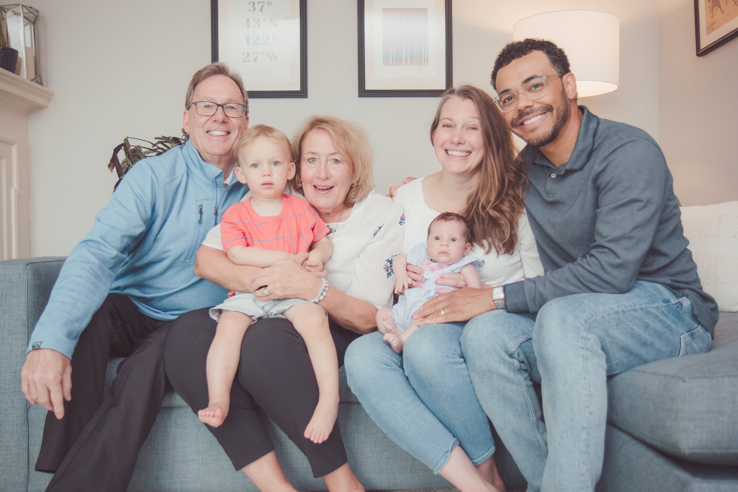 Family sitting together on a couch, smiling at the camera.