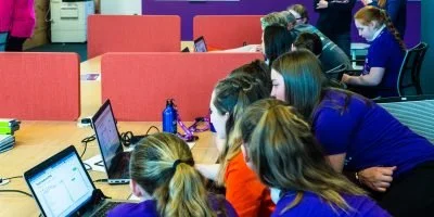 Group of students working together on laptops in a classroom