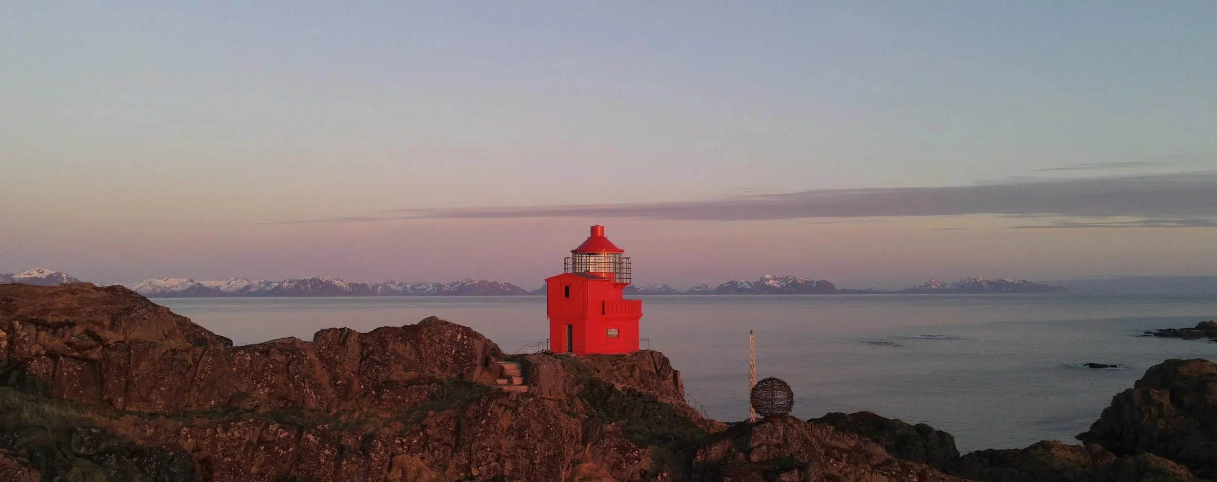 A bright red lighthouse at sunset.