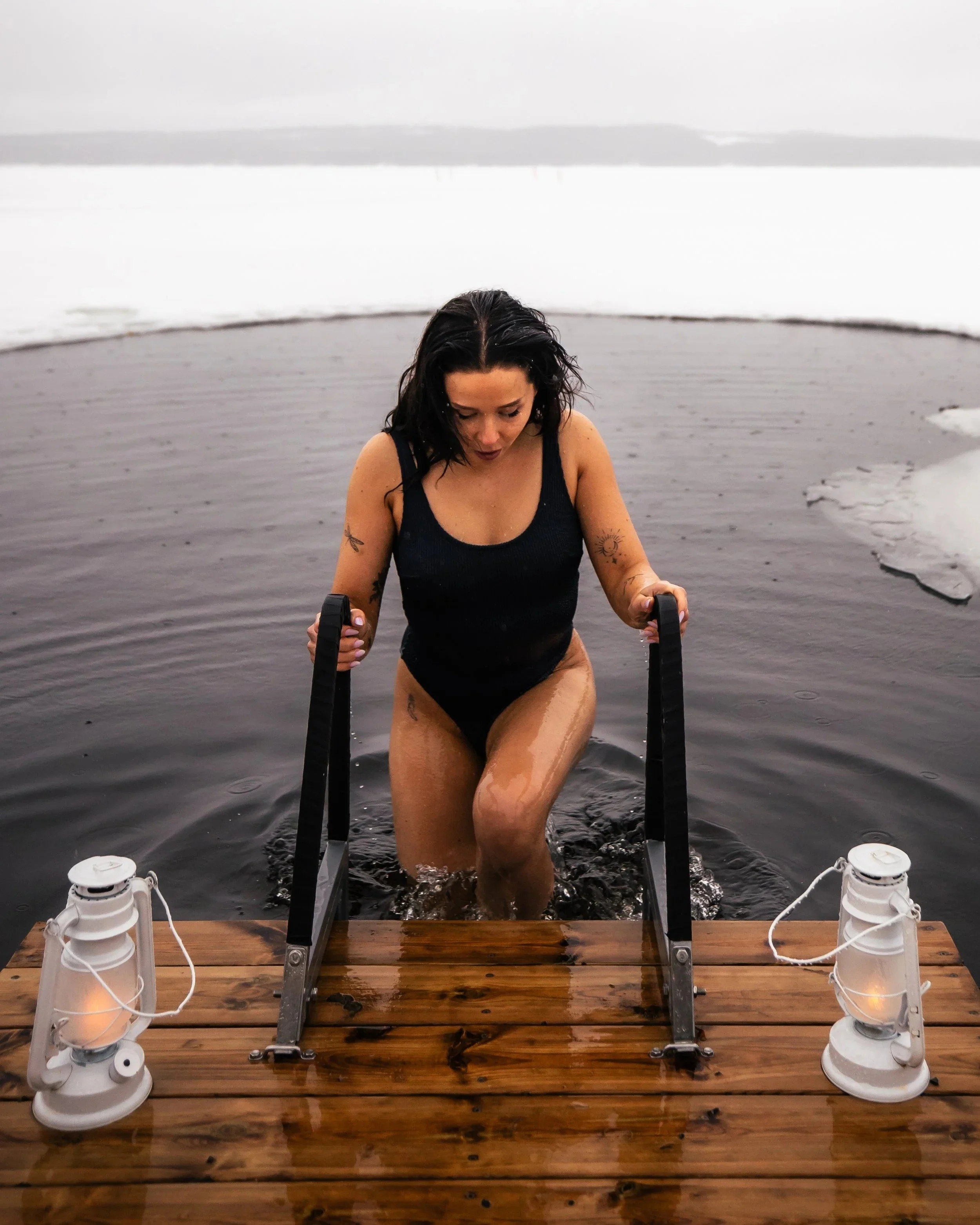 A woman in a black swimsuit ice bathing.