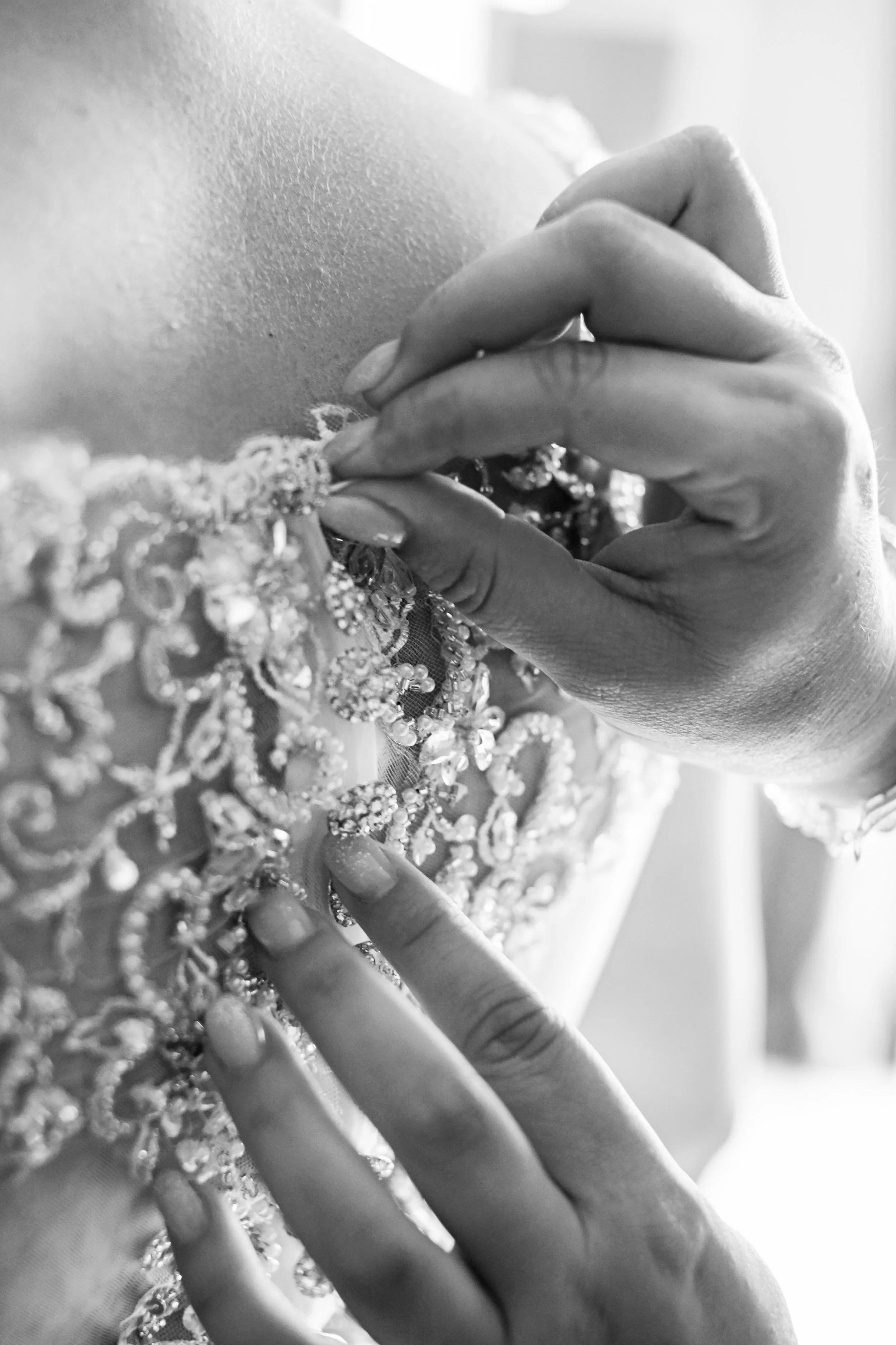 Black and white close up of brides buttons getting done of up from the back of brides dress