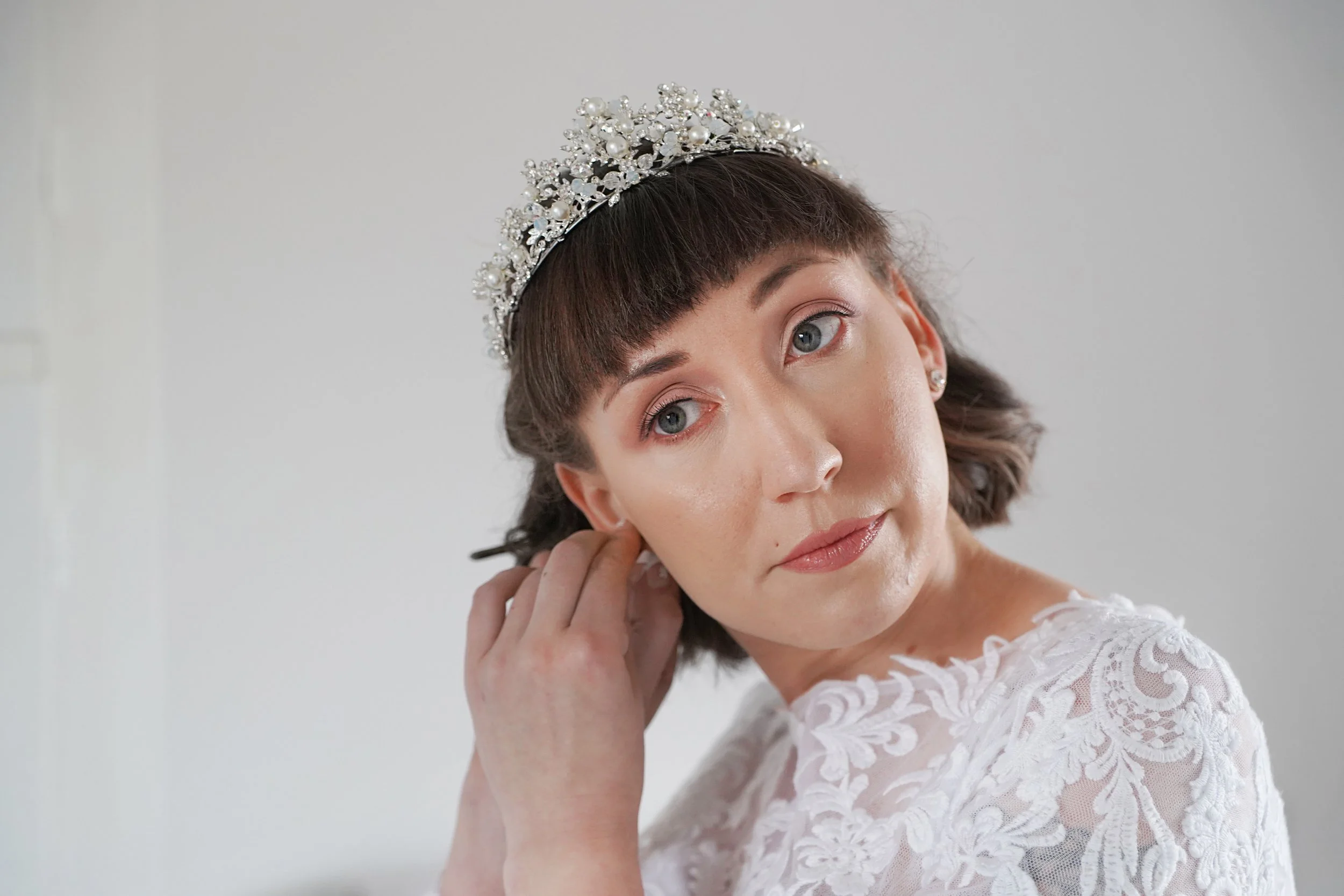 Bride doing her own earing, she is concentrating putting it in her ear