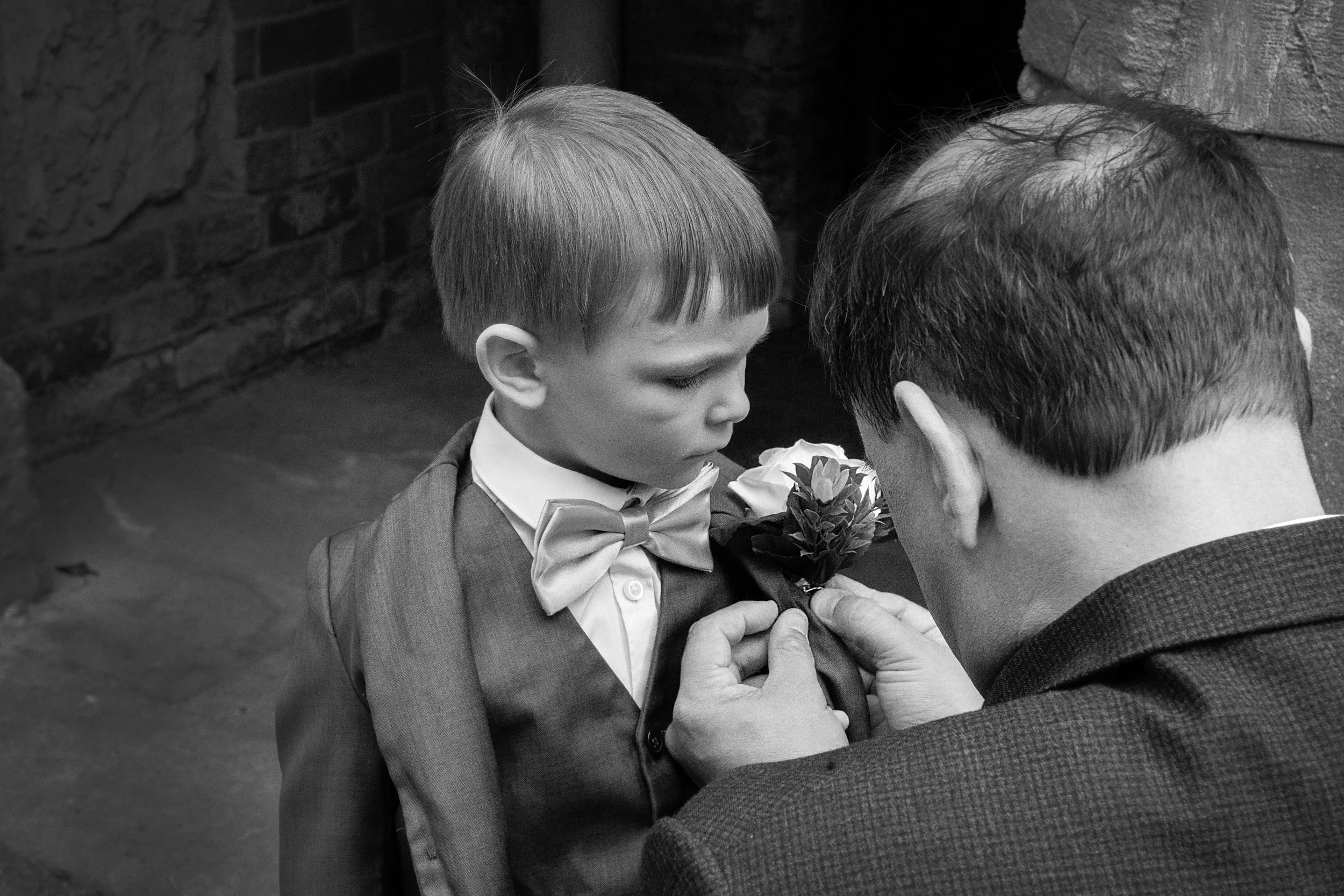 Black and white photo of dad doing young boys flower button