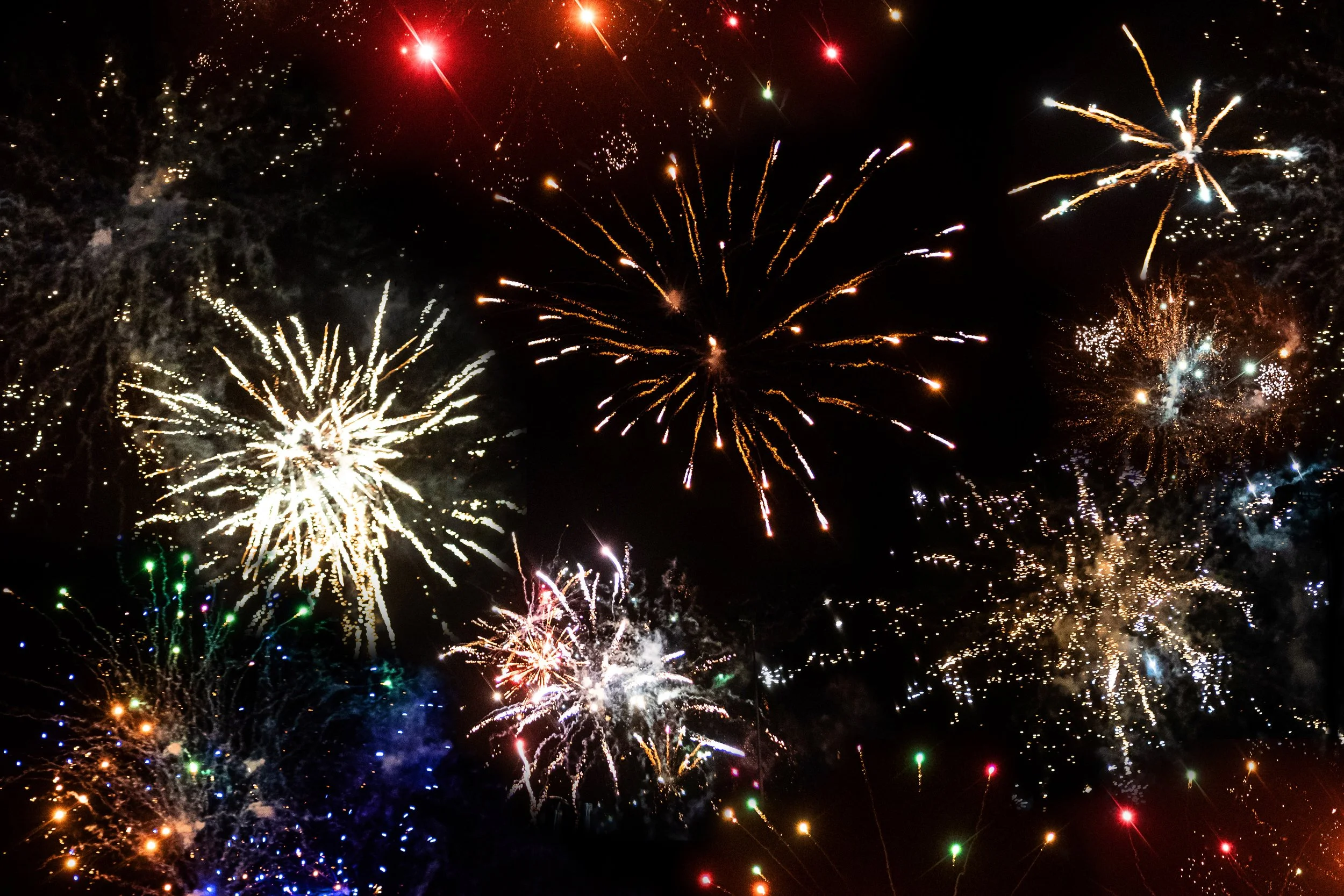 Fireworks exploding in the night sky with colorful bursts of light and sparks.