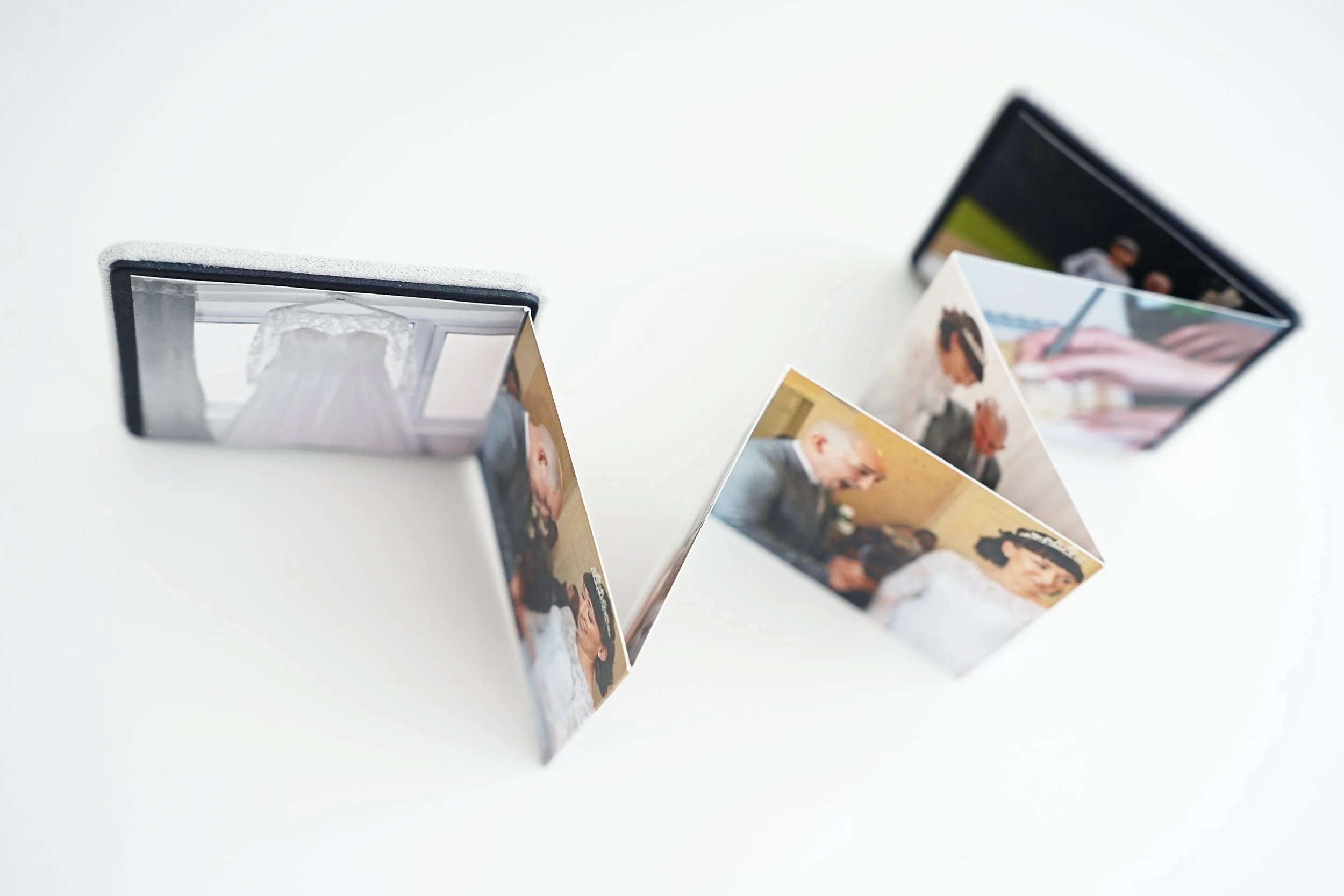 Three photo flipbooks on a white surface showing wedding photos of a bride, groom, and family members.