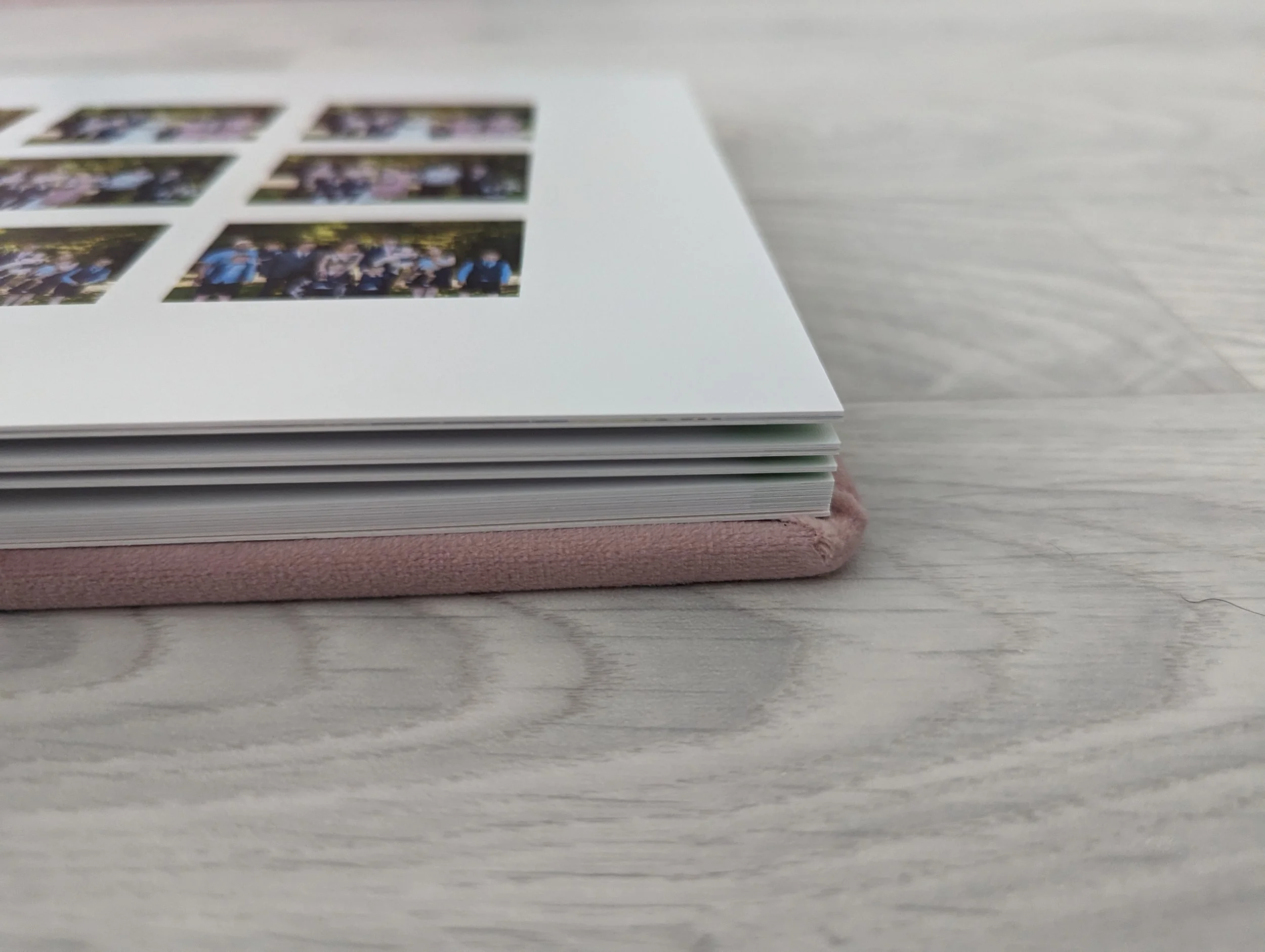 Close-up of a photo album lying on a light wooden surface, with several photo pages visible.
