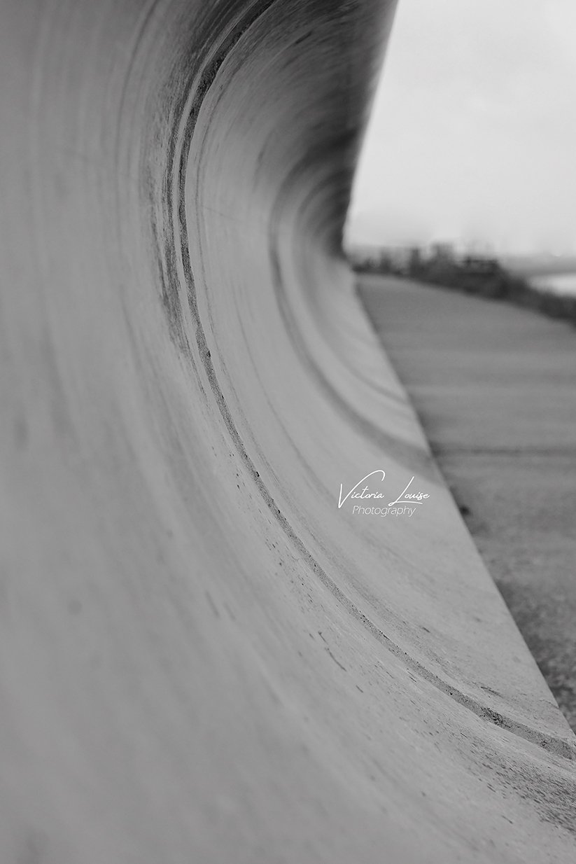 Close-up of a large, cylindrical concrete pipe with the opening facing the viewer, taken in black and white.