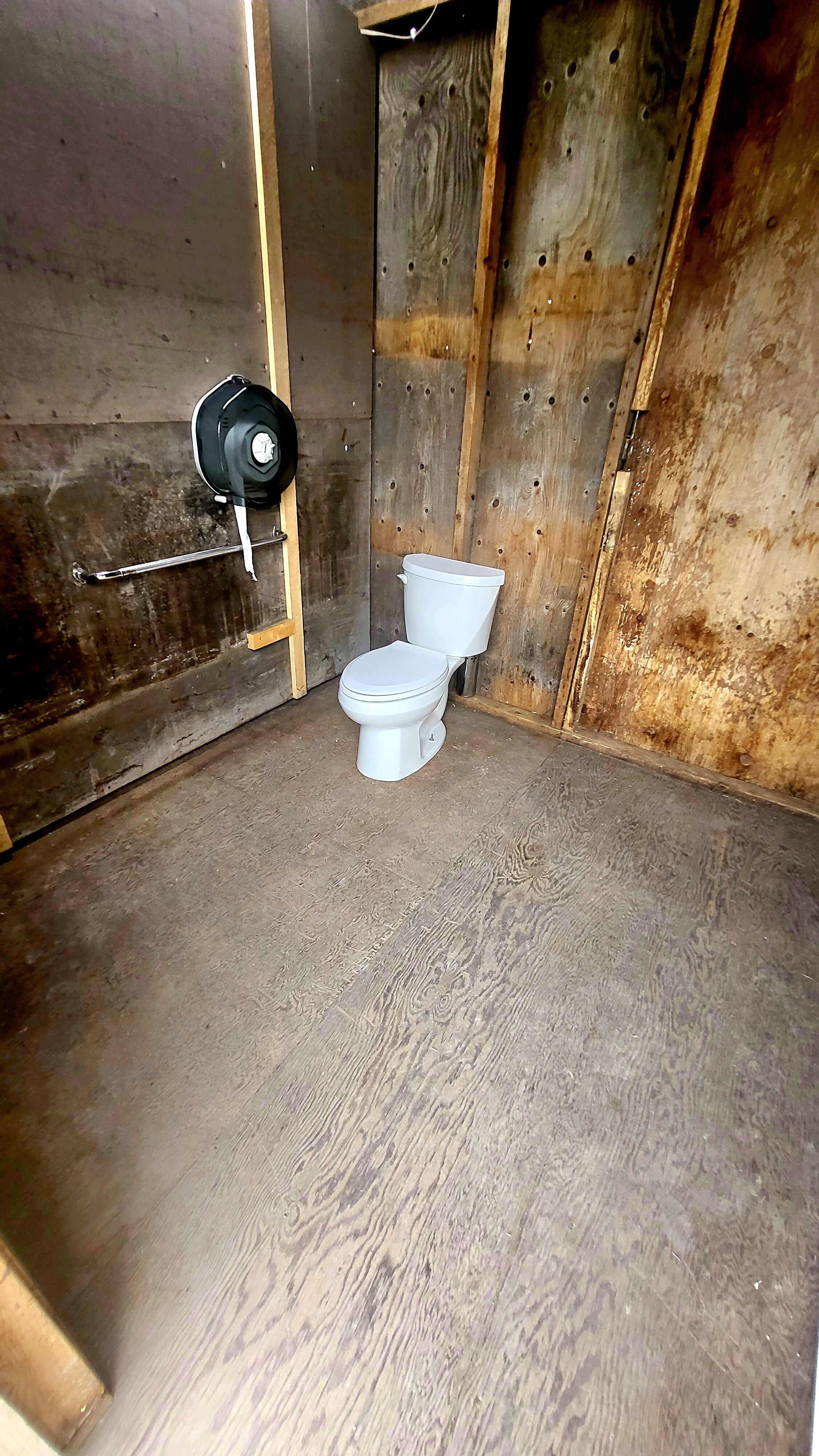 photo of the inside of the large toilet stall with a toilet and railing in frame.