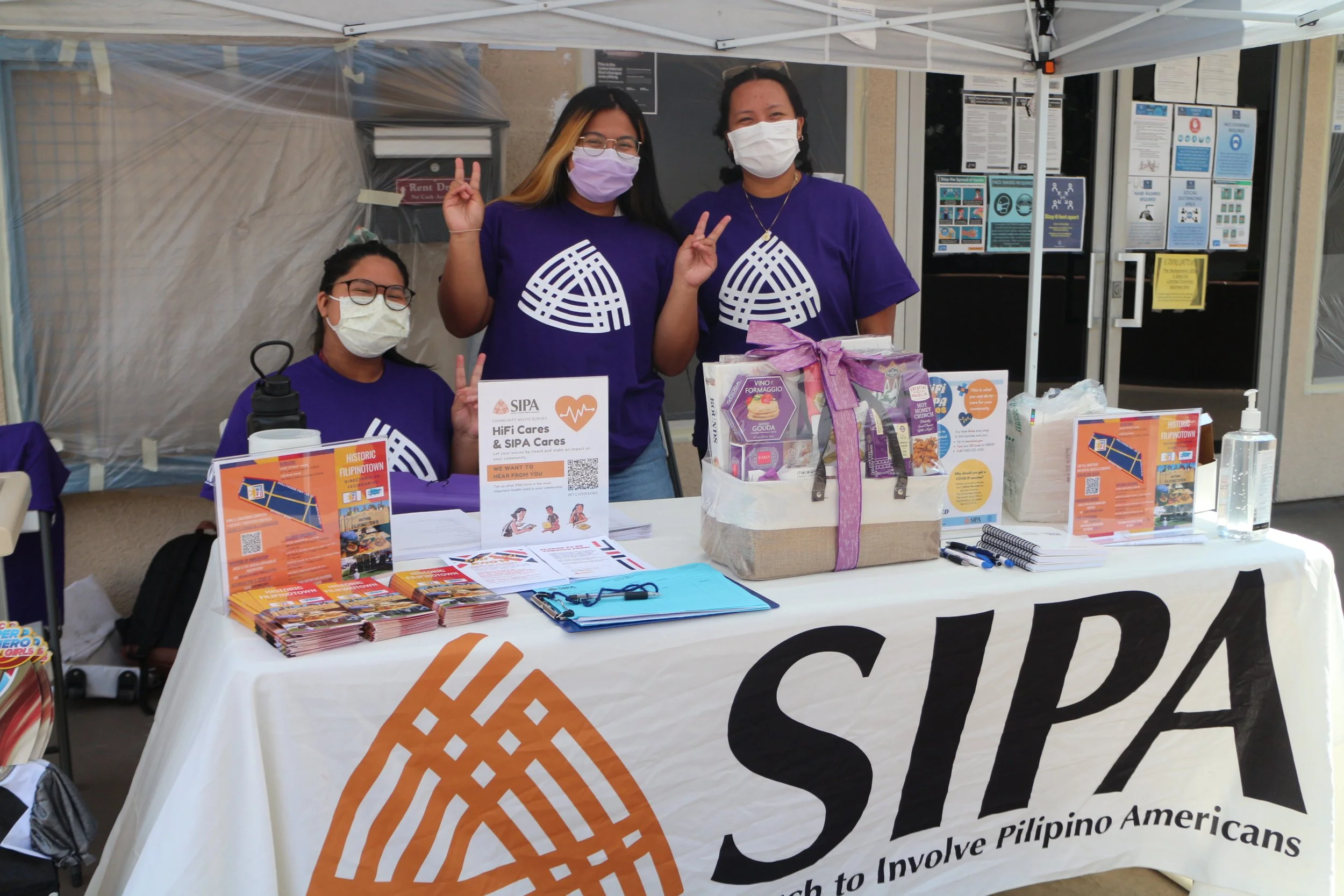 People masked wearing purple SIPA shirts while tabling for an event.