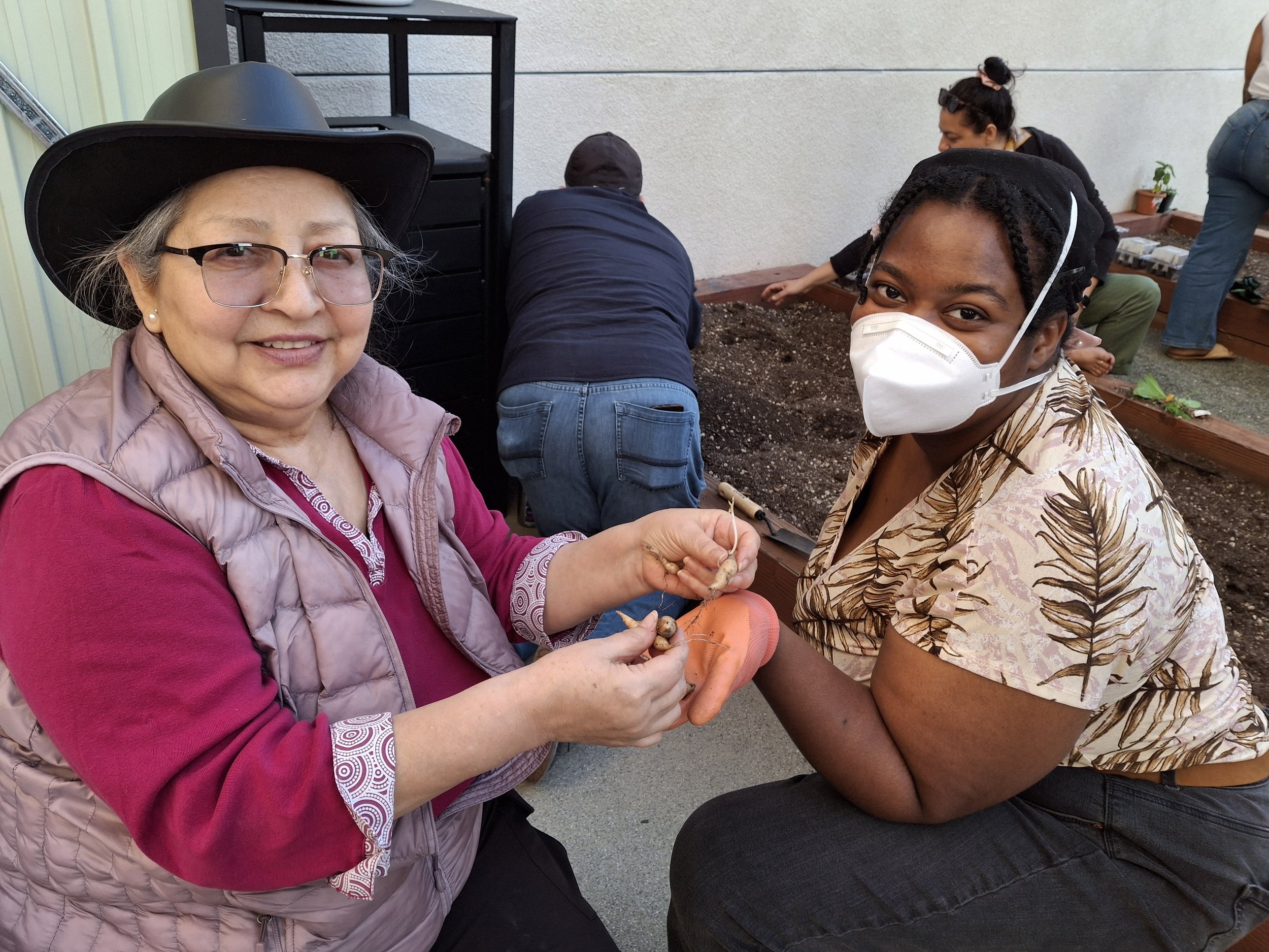 Two female garden participants show off a seedline
