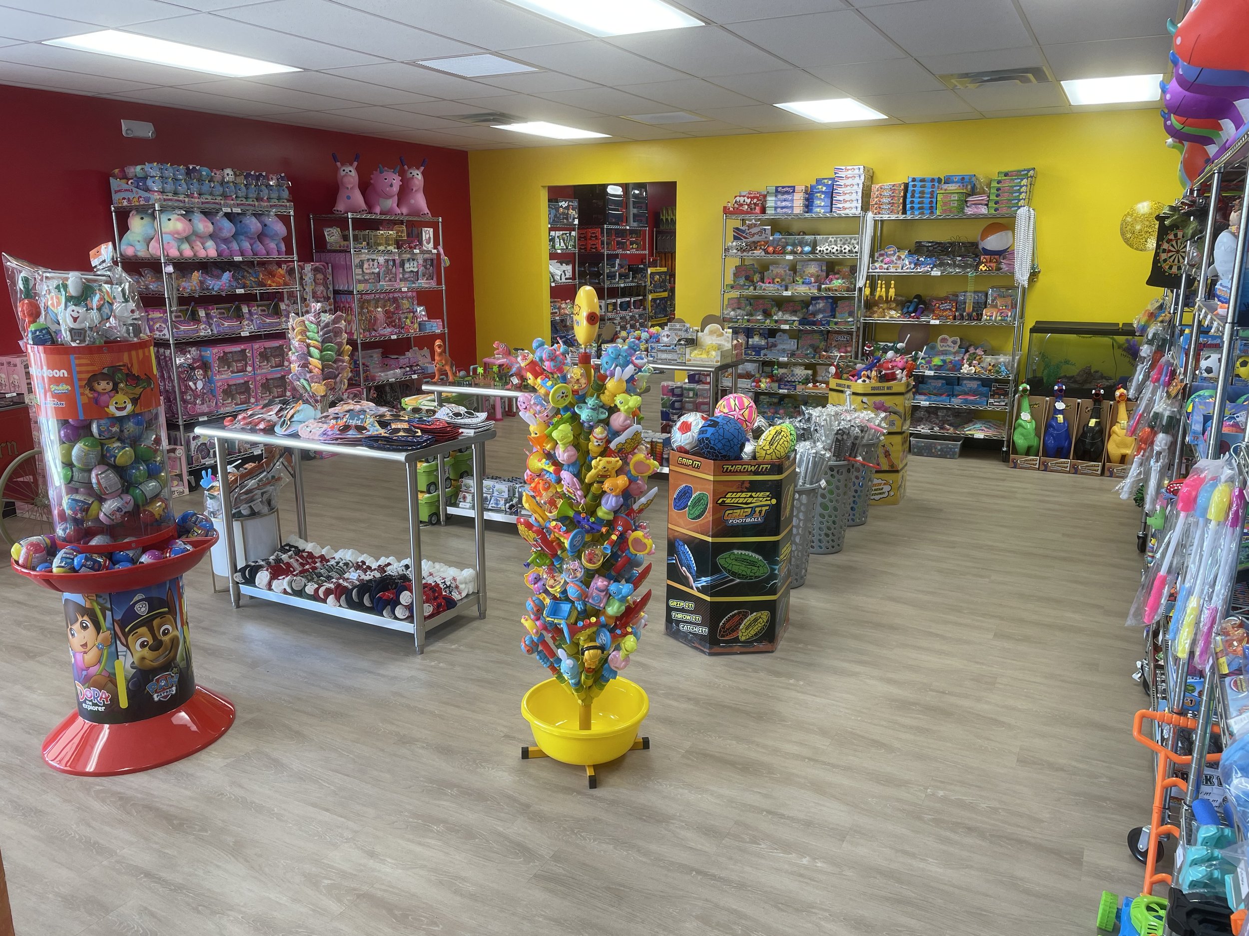 Interior of a toy store with shelves filled with toys and games, colorful display stands, and a yellow and red wall.