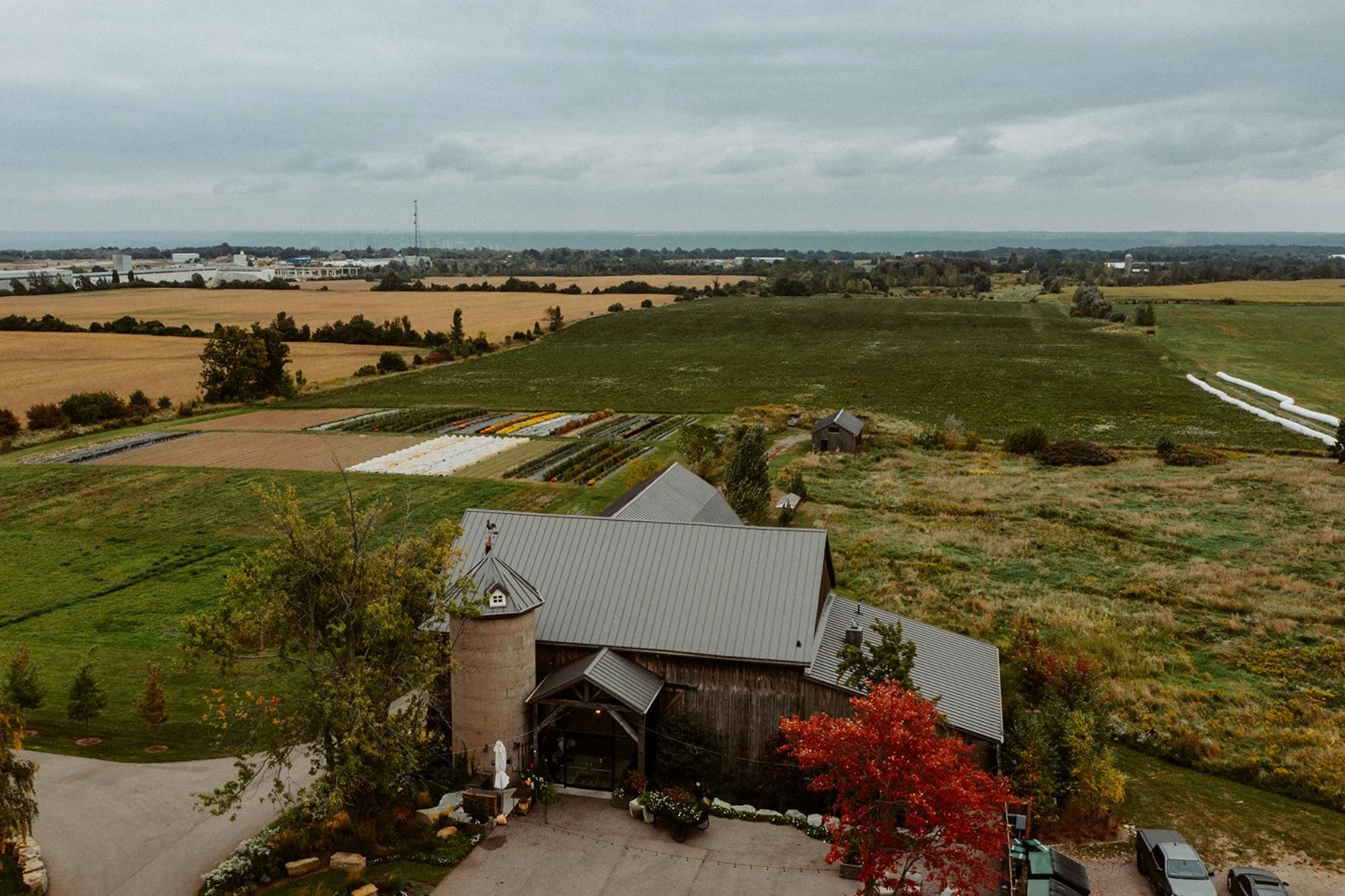 Aerial view of a barn venue surrounded by fields, gardens, and open farmland.