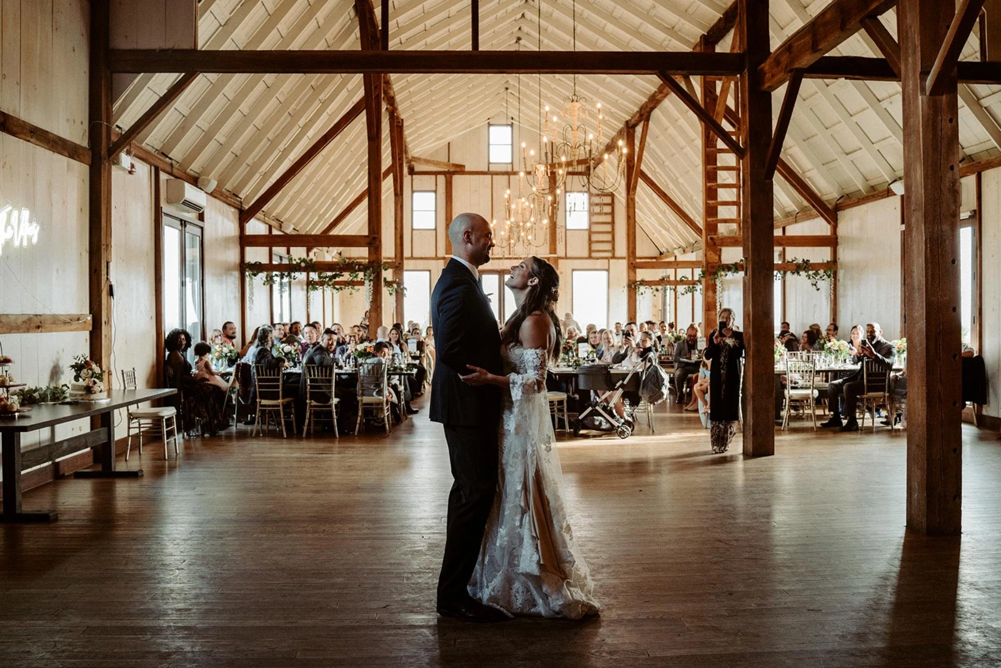 Bride and groom share their first dance in the center of the barn reception hall.