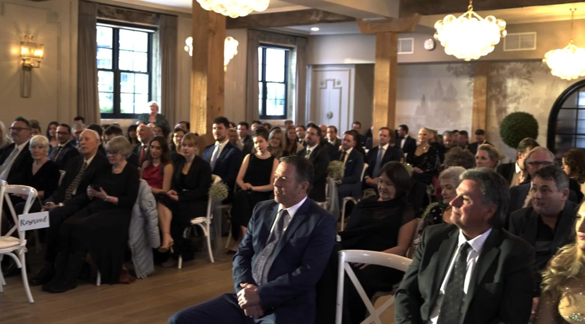Guests seated inside the ceremony room watch attentively.