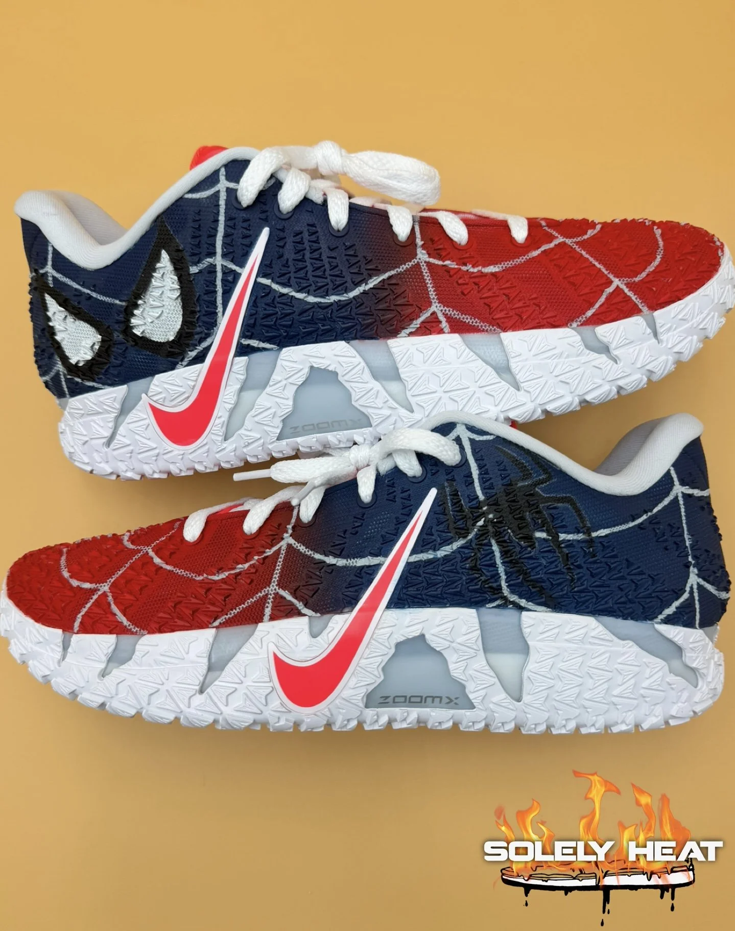 Two red, white, and navy custom painted athletic shoes against an orange background