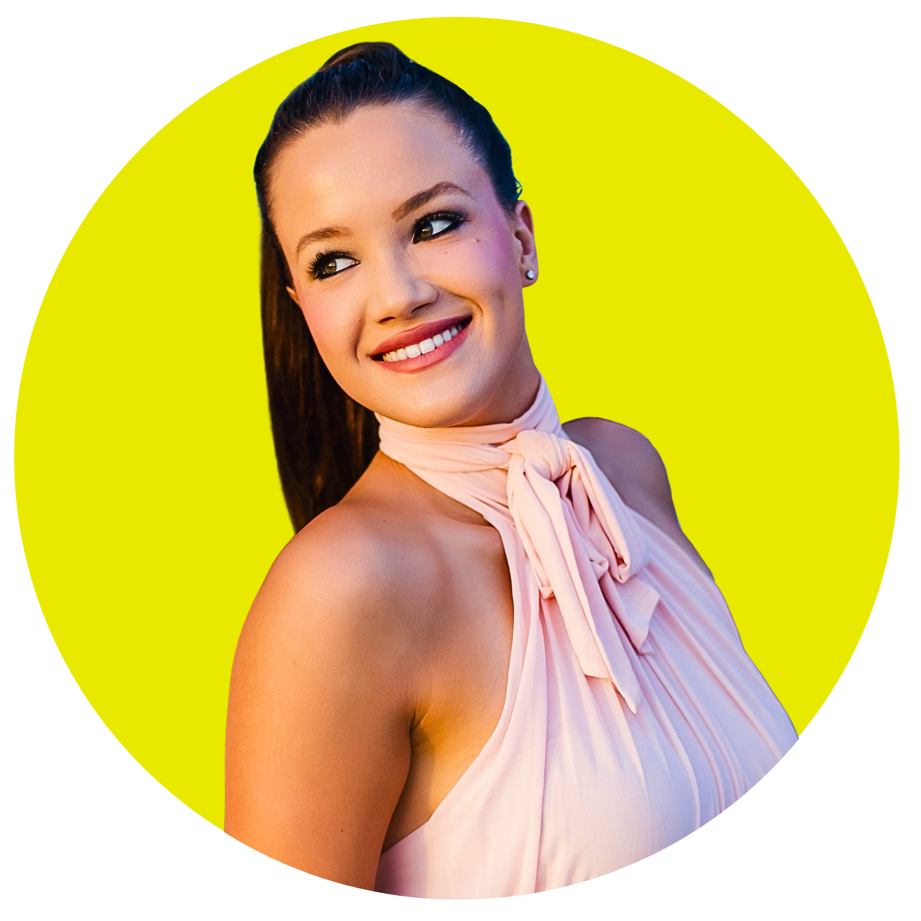 A woman with dark brown hair pulled back, smiling with white teeth, wearing pearl earrings and a pale pink halter dress with a tied ruffle at the neck, standing against a bright yellow background inside a black circular frame.