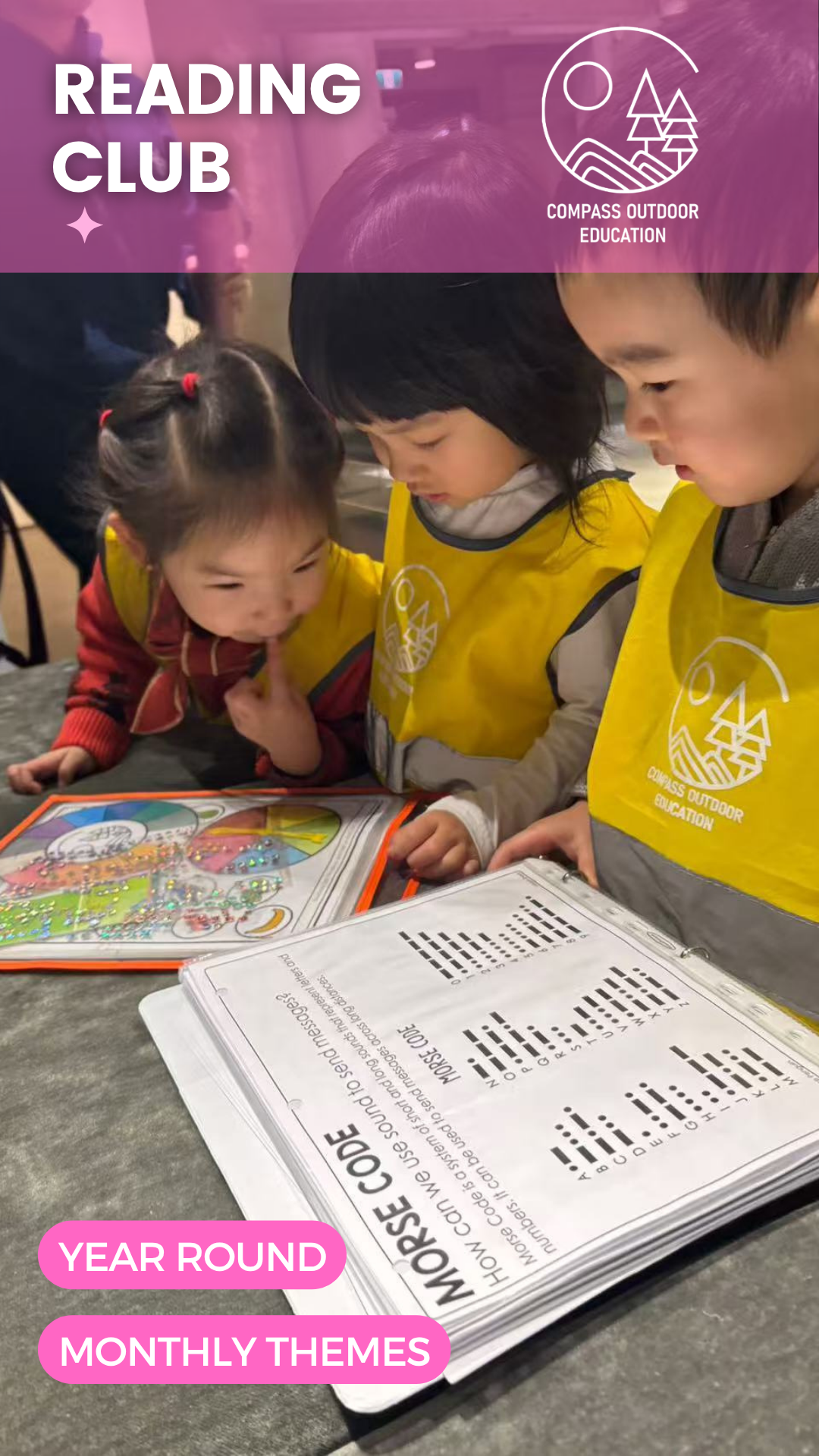 Three young children in yellow Compass vests leaning in close together to read a Morse code activity book at Compass Outdoor Education Reading Club.