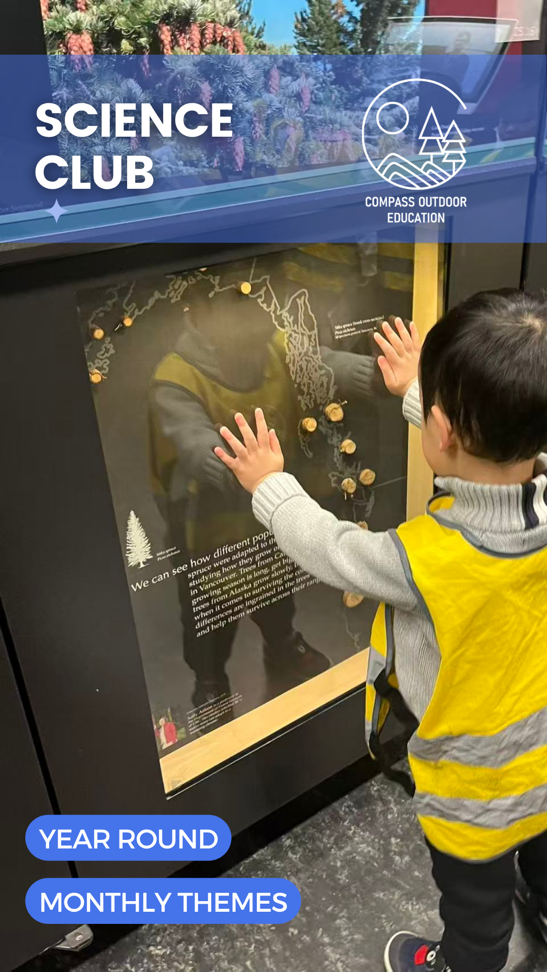 A young child in a yellow Compass safety vest exploring an interactive tree-rings exhibit with both hands at a Vancouver museum during Compass Outdoor Education Science Club.