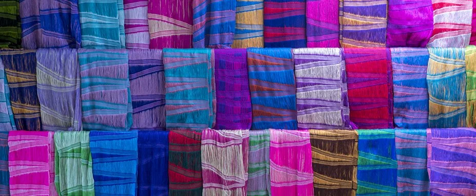 Écharpes colorées en soie ou en coton avec des motifs rayés, suspendues en rangées.