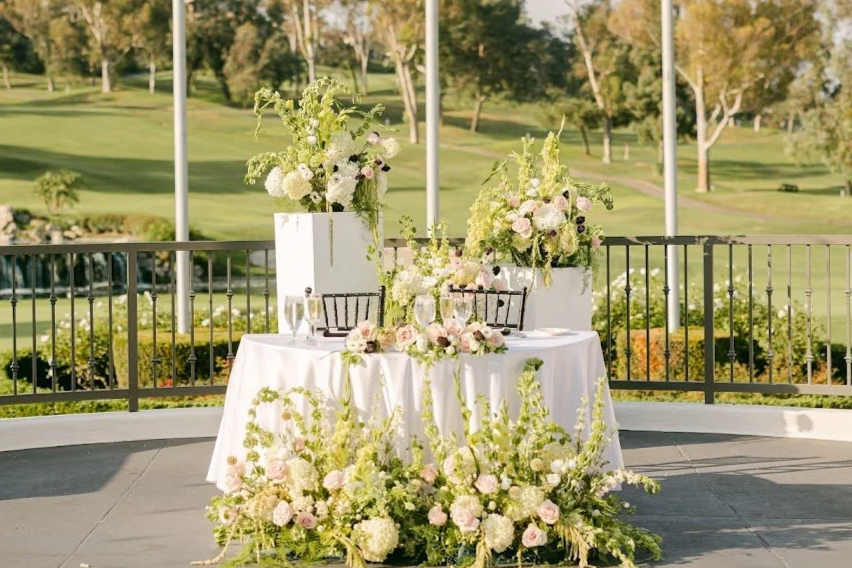 Ceremony large green and white floral pieces relocated to the sweetheart table.