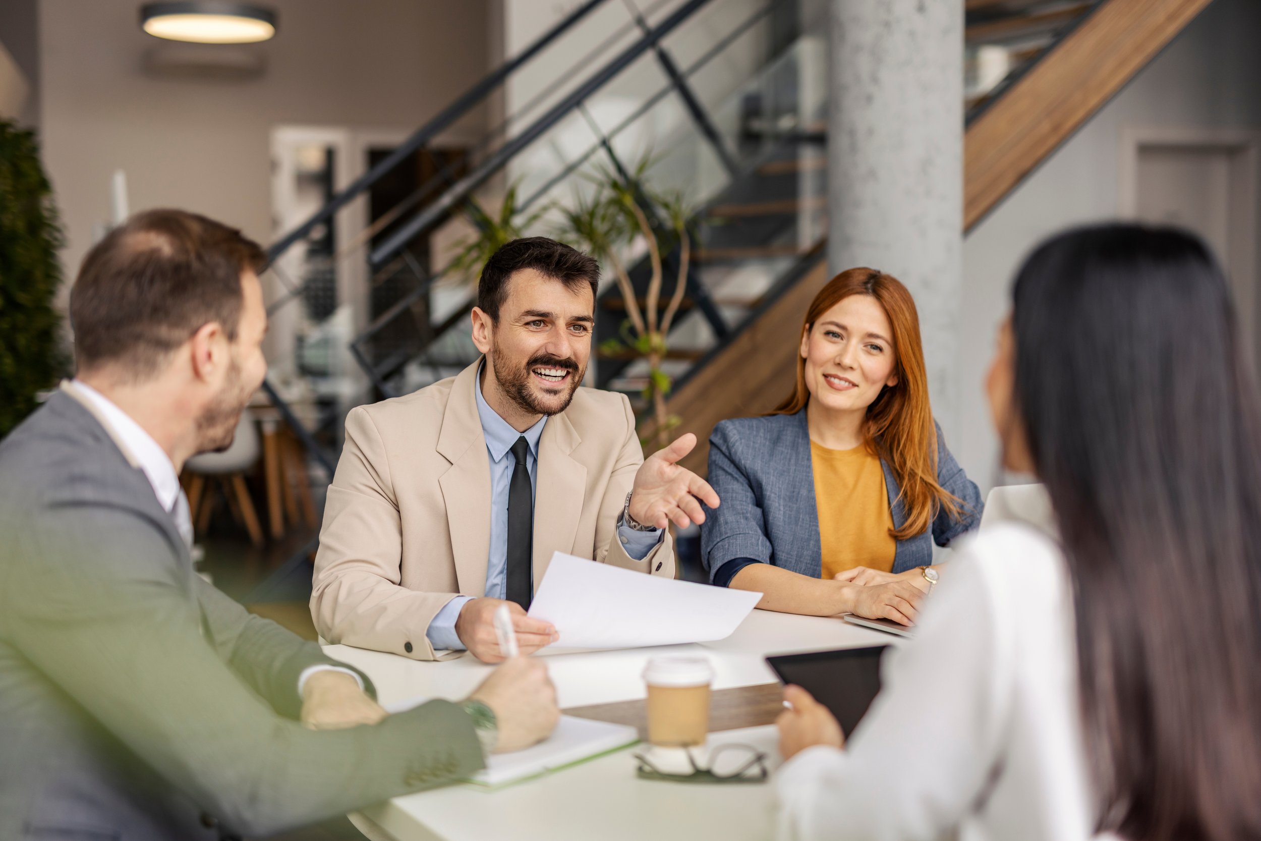 Four professionals seated at an office table with financial documents in front of them.