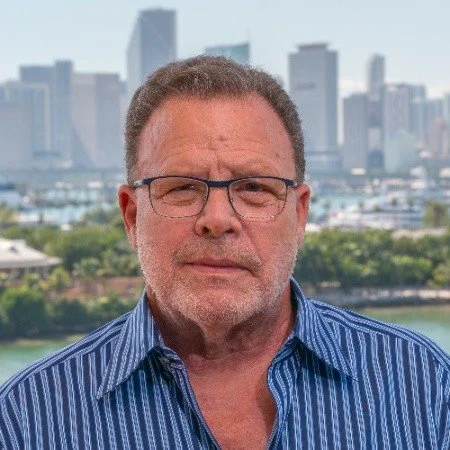 Roger Craver, with a cityscape and park behind him.