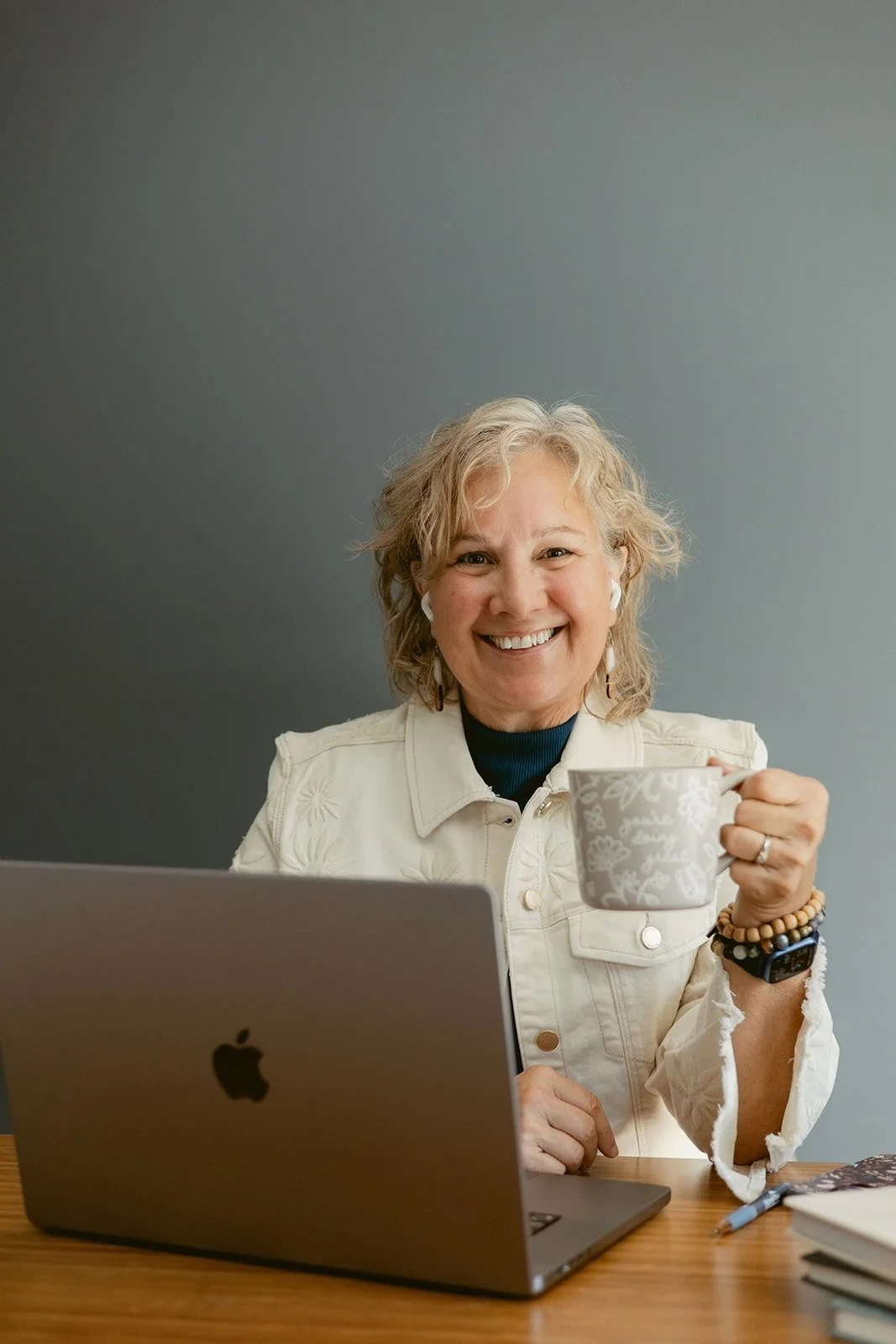 Business coach Cathy Fitzgerald smiling at the camera with her laptop and a mug of coffee