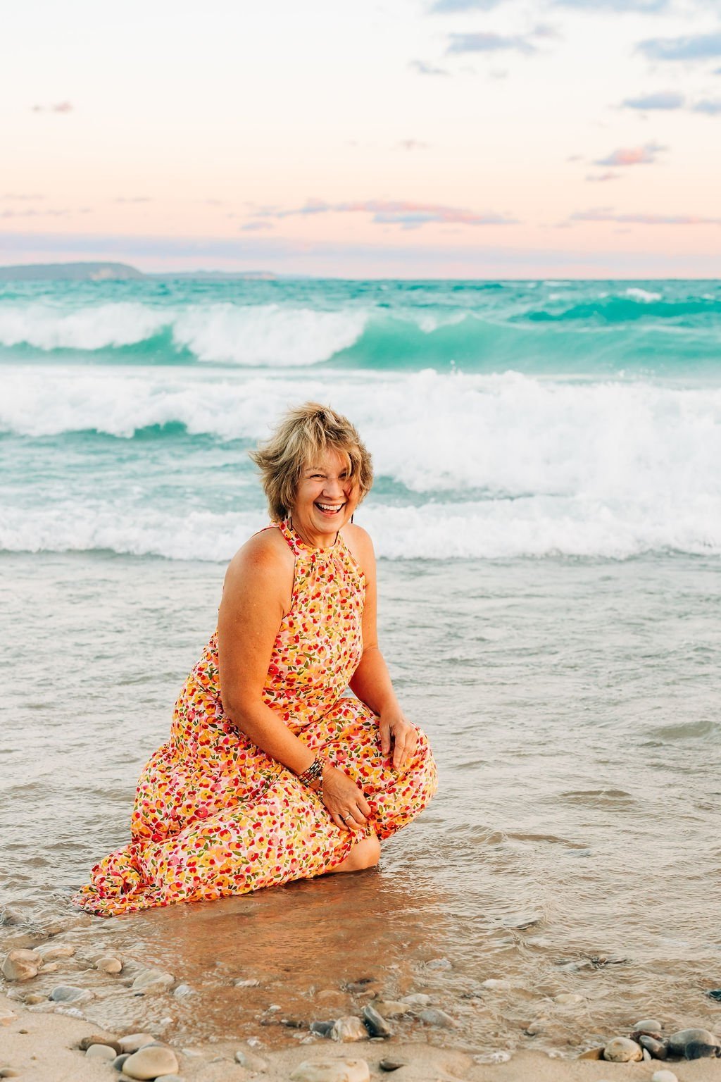 Cathy, Age Wild life coach laughing in the sand at the edge of Lake Michigan