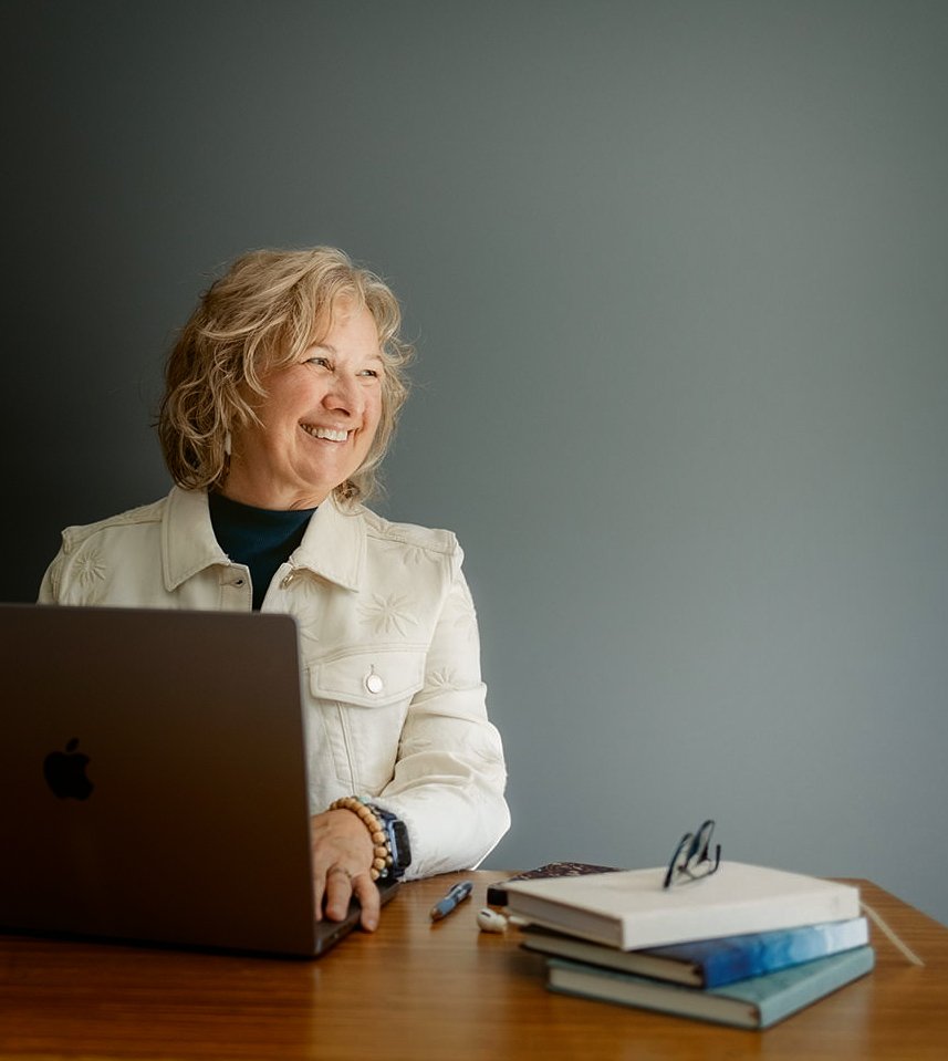studio business coach Cathy Fitz sitting at laptop and smiling to the side