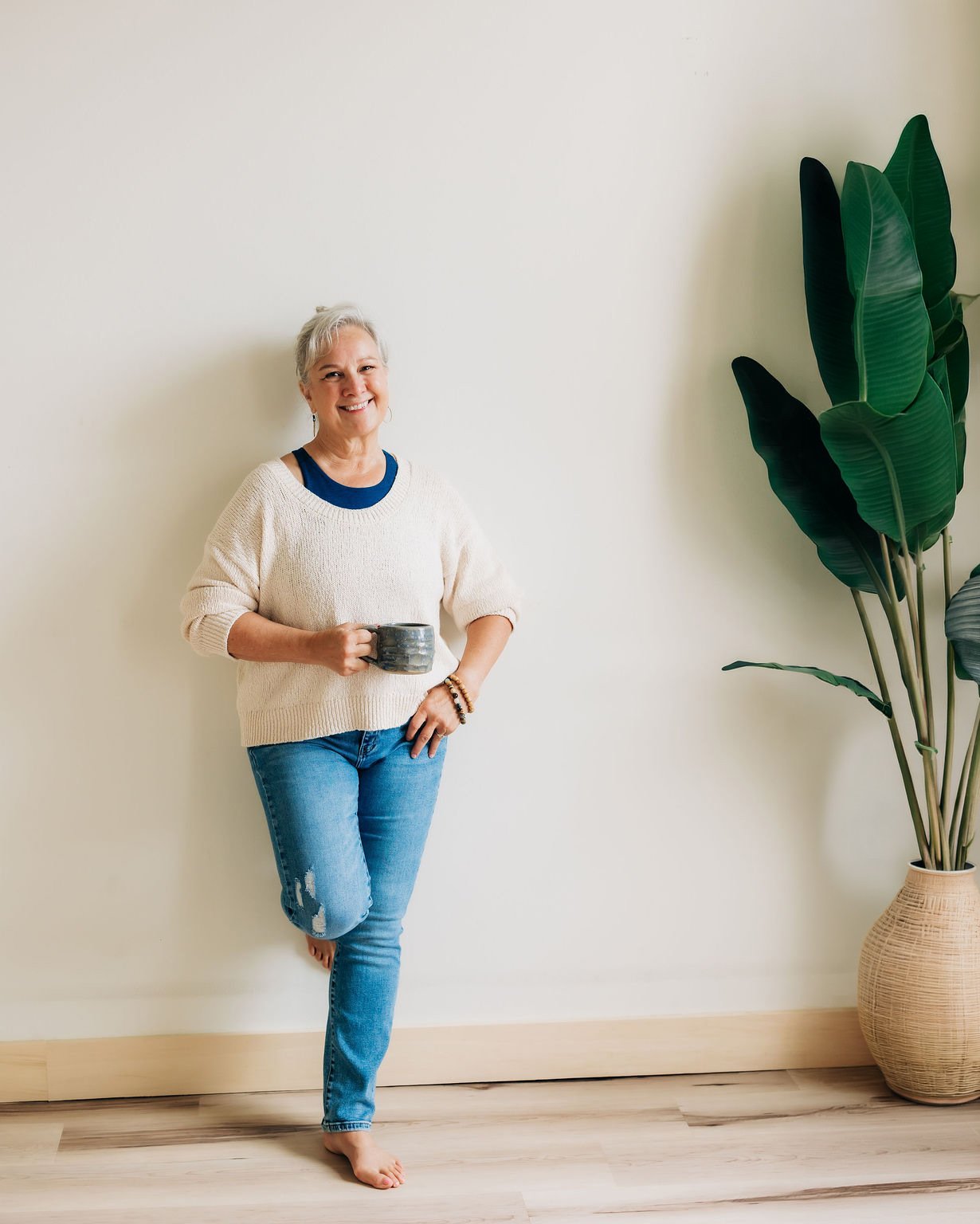 Cathy Fitzgerald, Studio business coach, leaning against the wall and smiling with a cup of coffee