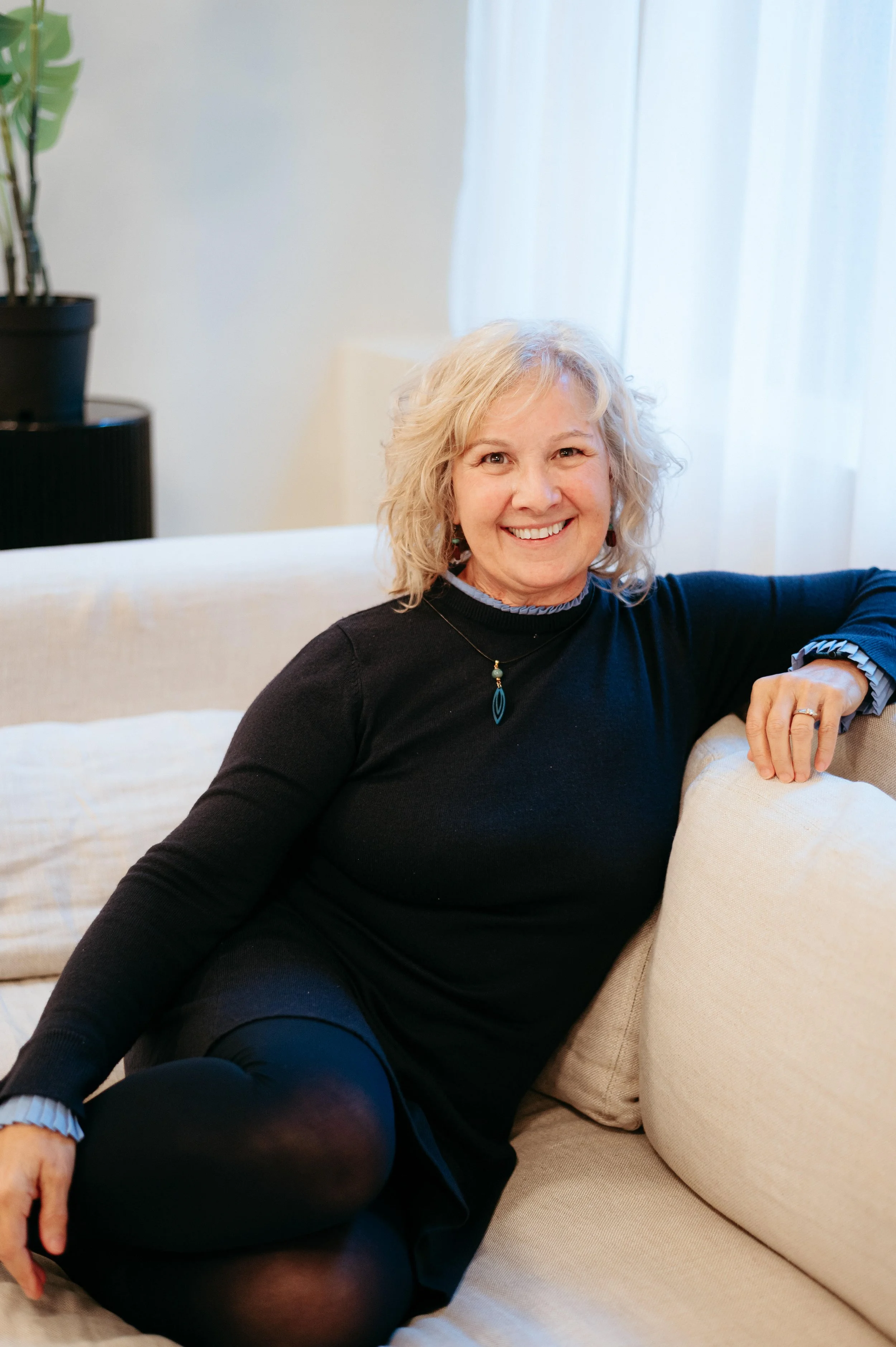 Cathy Fitzgerald studio business coach sitting on couch and smiling