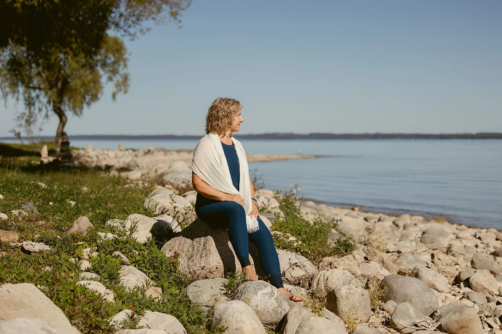 Life coach Cathy Fitzgerald sitting on rocks looking out at Lake Michigan