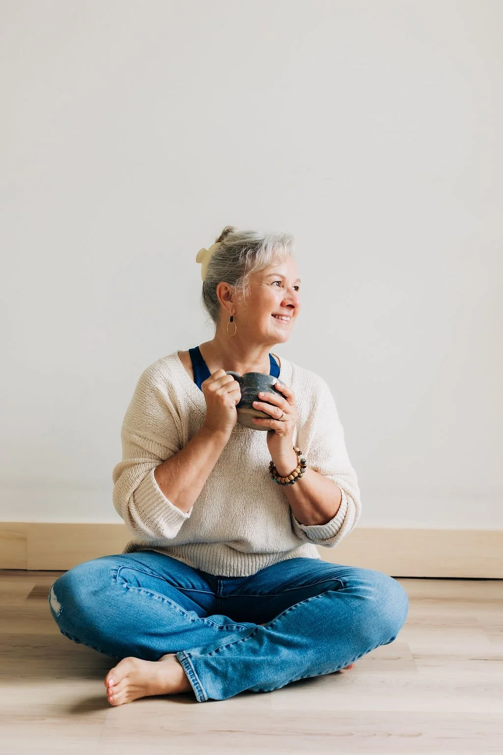 Cathy Fitzgerald, Business coaching, sitting on the floor, holding a coffee mug, looking to the side and smiling