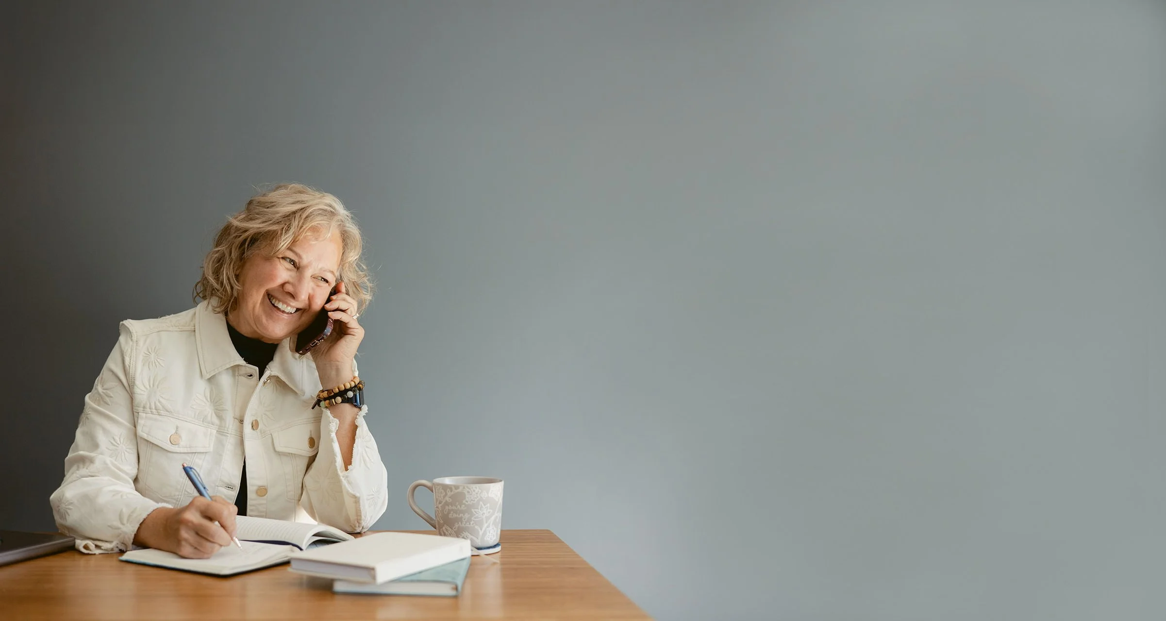 Studio business coach Cathy Fitzgerald talking on the phone and smiling with a client