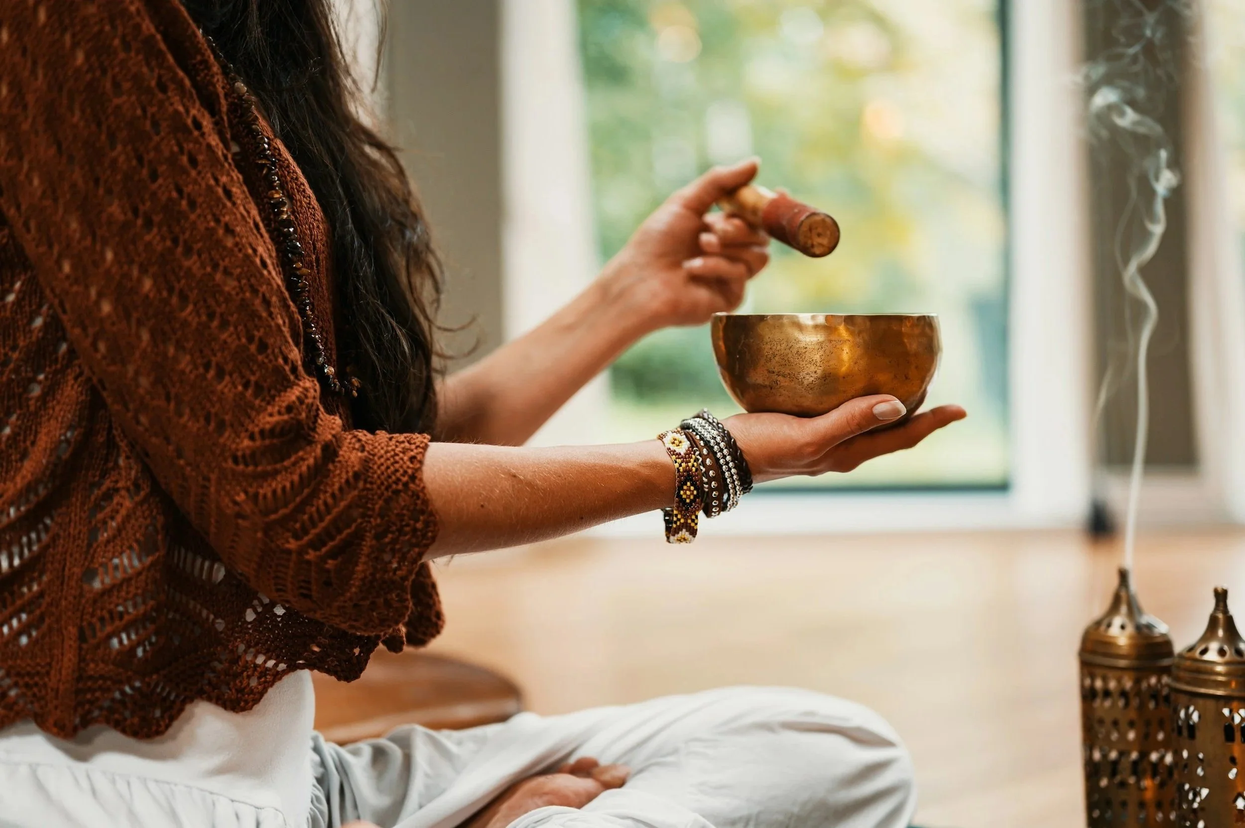 woman sitting on floor holding a sound bowl.