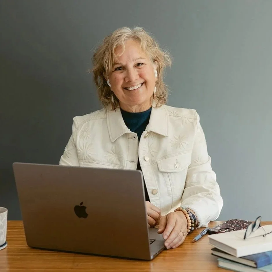 Studio Business Coach Cathy Fitzgerald smiling in front of her laptop