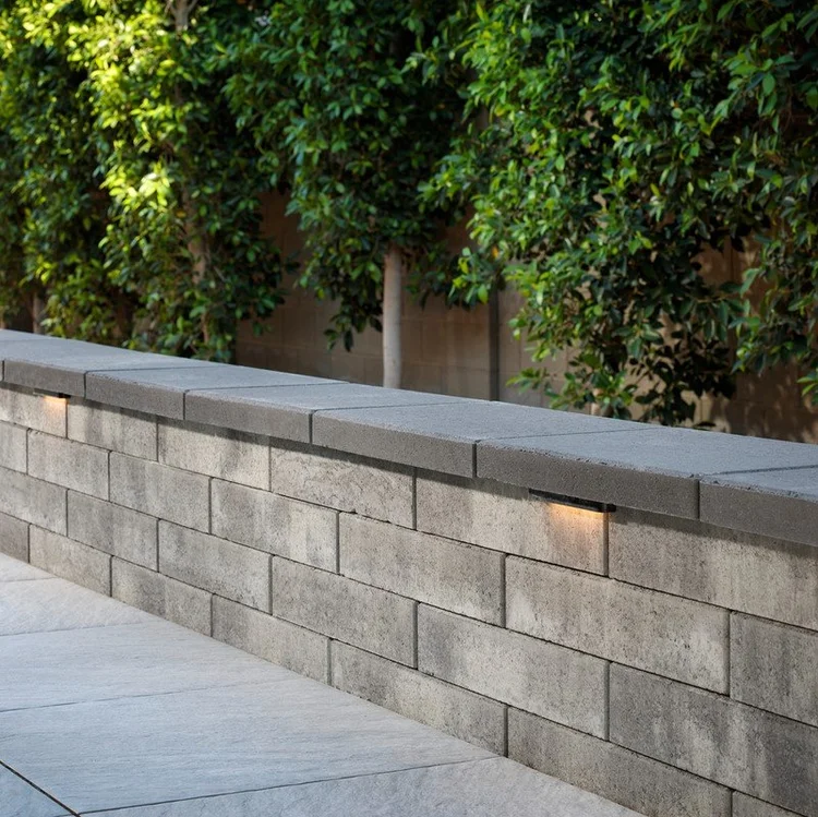 Concrete block retaining wall with a cap and built-in lights