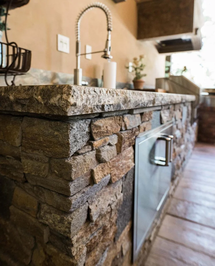 Close-up of an outdoor kitchen counter with stacked stone veneer and a stone top