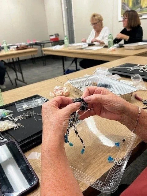 Hands working on a beaded art project at an adult workshop