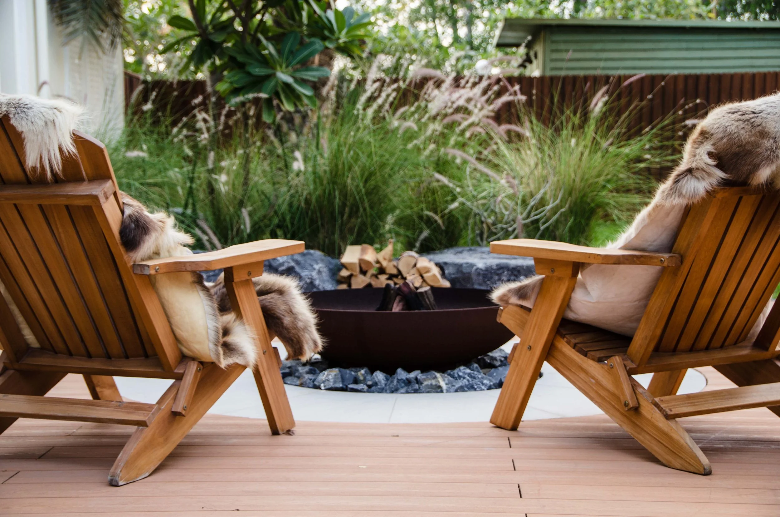 A spacious wooden deck features a central fire pit area optimized for social gatherings.