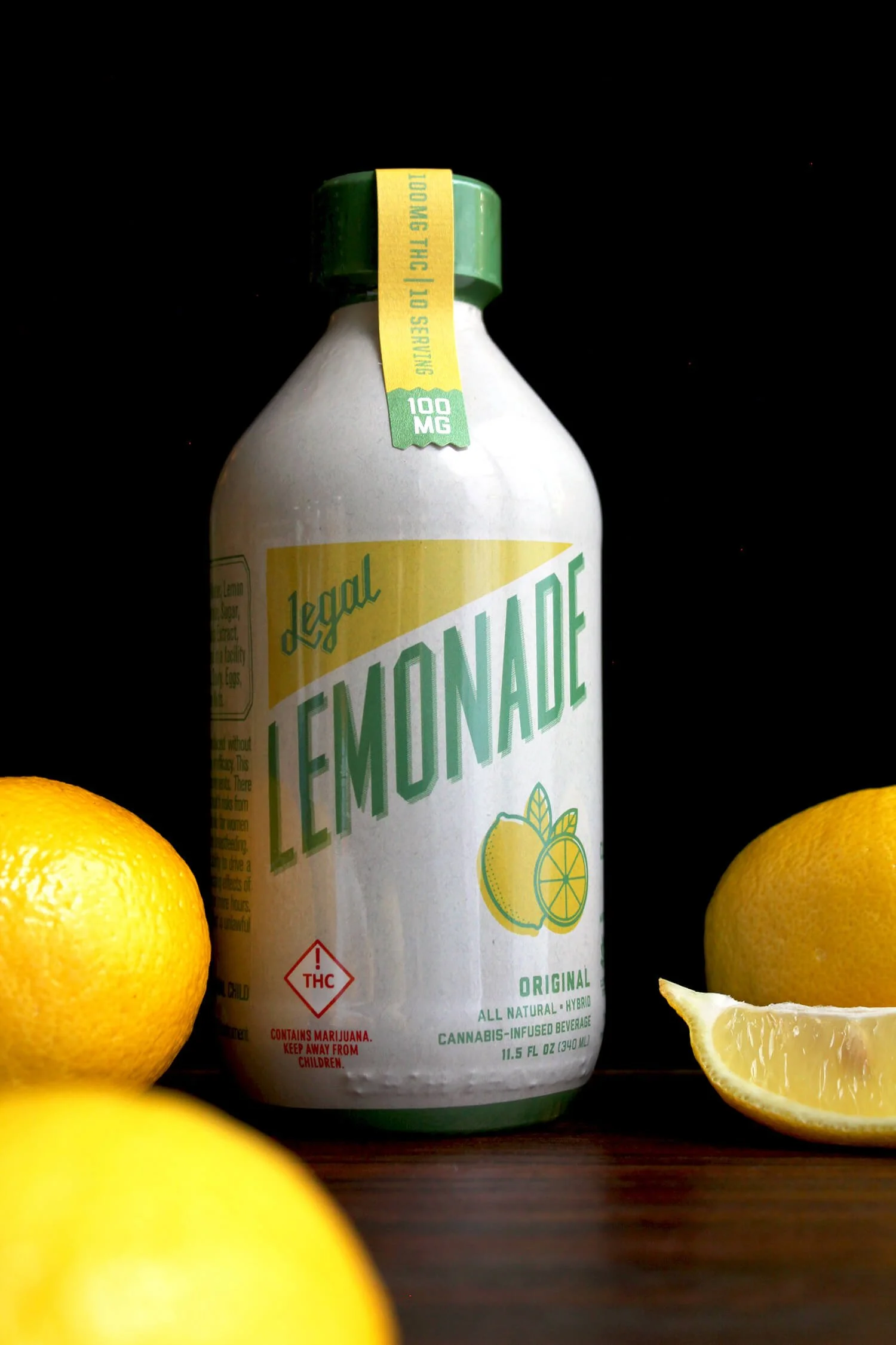 A bottle of lemon-lime flavored beverage surrounded by whole and sliced lemons on a dark surface.