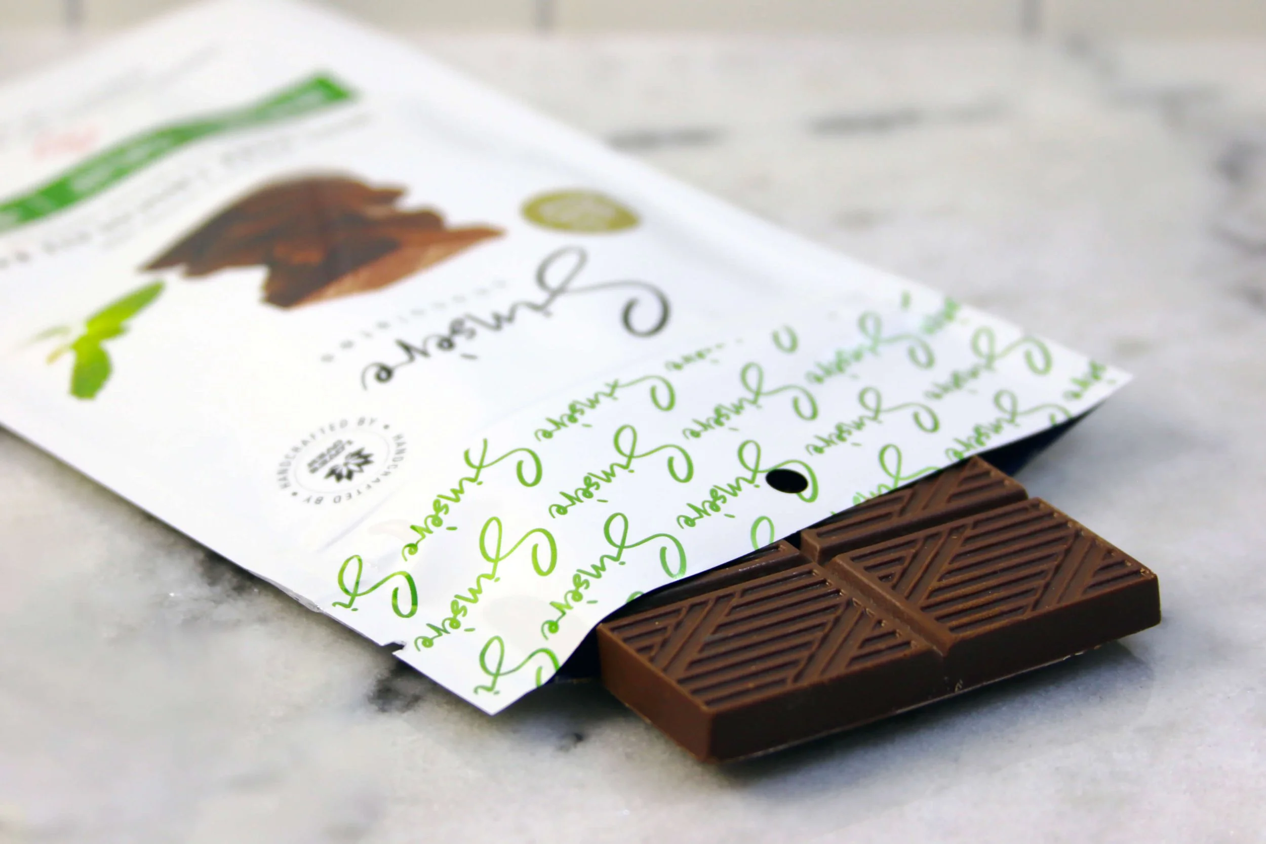 A partially unwrapped chocolate bar with decorative packaging on a marble surface.
