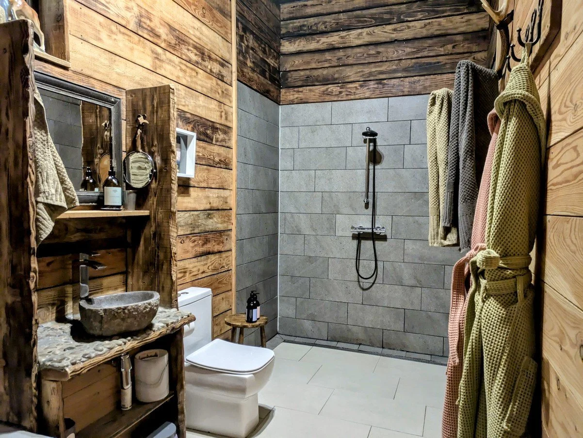 Relax in Alpnhaus’s serene bathroom with a walk-in shower, Molton Brown products, and warm larch wood walls for true tranquillity.