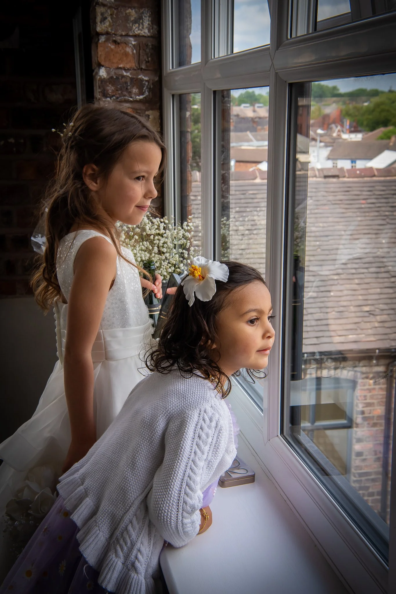 bridesmaids look out of the window at their newly married parents after their wedding ceremony at spode potbank wedding venue in stoke on trent