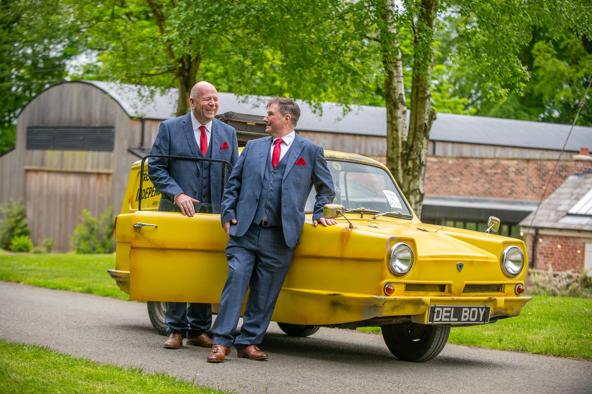 groom and best man pose with their only fools and horses 3 wheeler wedding car at foxtail barns in consall staffordshire photographed by UK wedding photographer chris peach photography