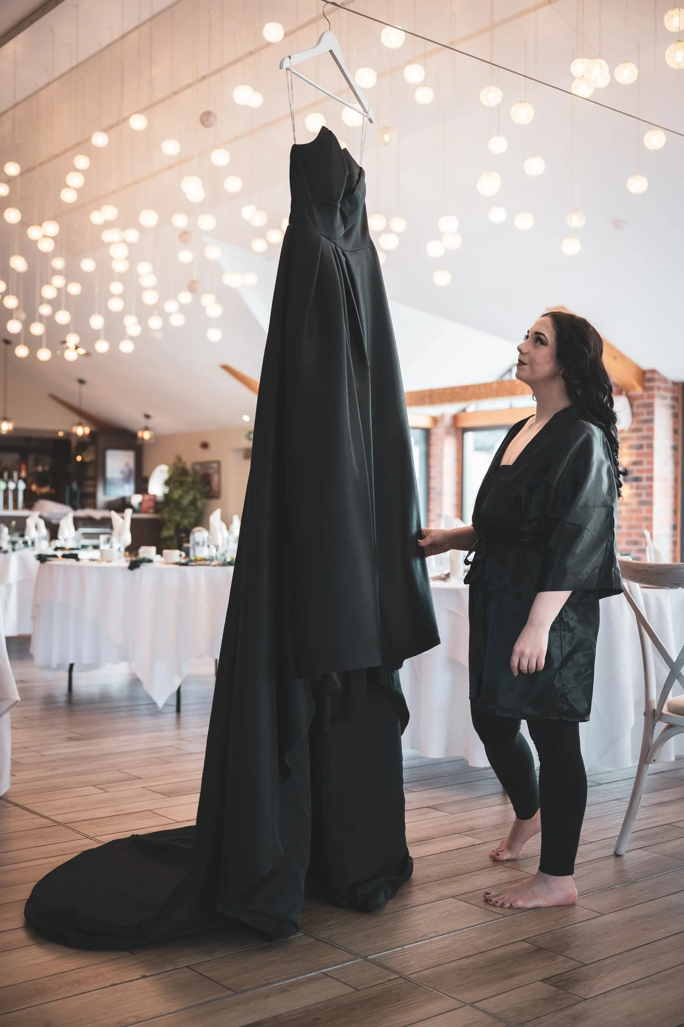 bride looks at her black wedding dress during a bridal prep shoot at the boathouse wedding venue at aston marina in stone staffordshire photographed by wedding photographer chris peach photography