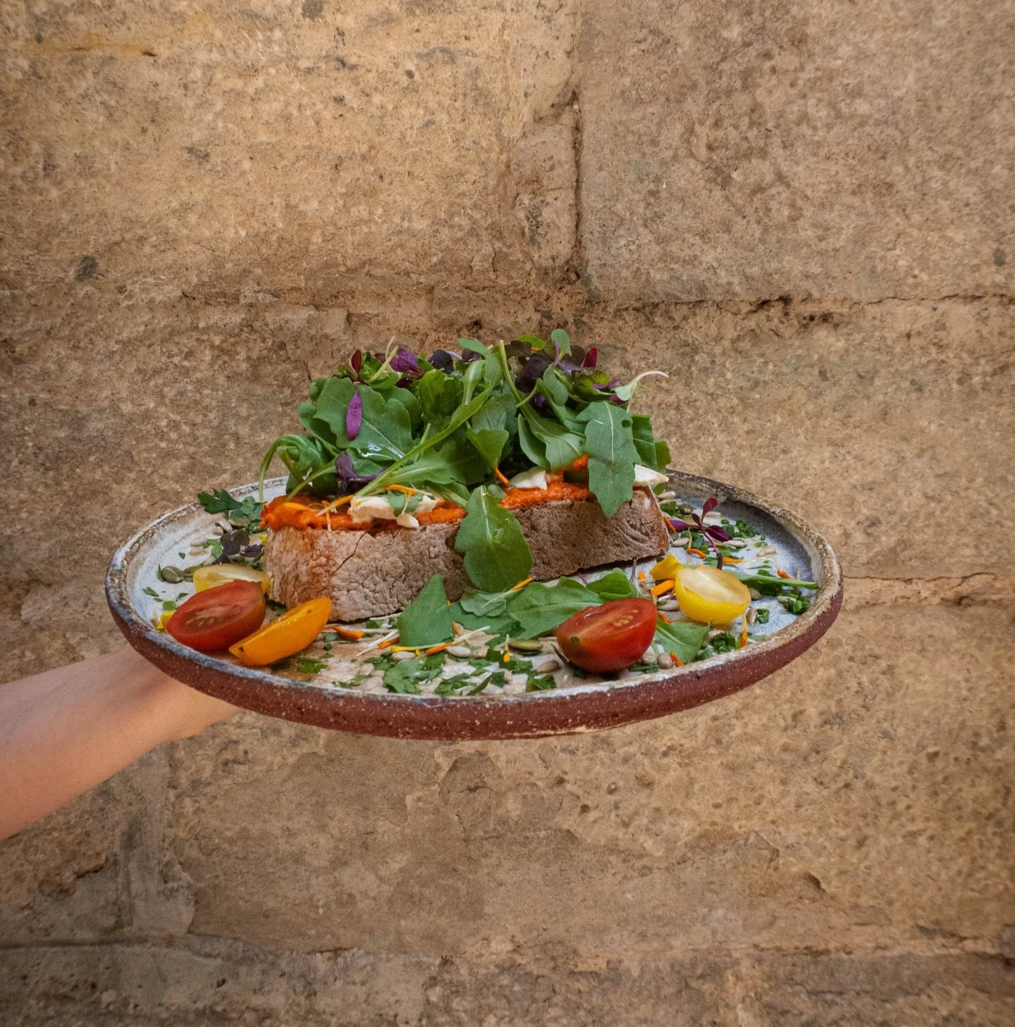 Muhammara spread on a piece of @la.puntual sourdough bread, topped with cherry toms, tofu, toasted seeds &amp; lot&rsquo;s of green ( as is it&rsquo;s vegan ) but if you fancy you can always add two poached eggs or a side of bacon! ( also gluten free