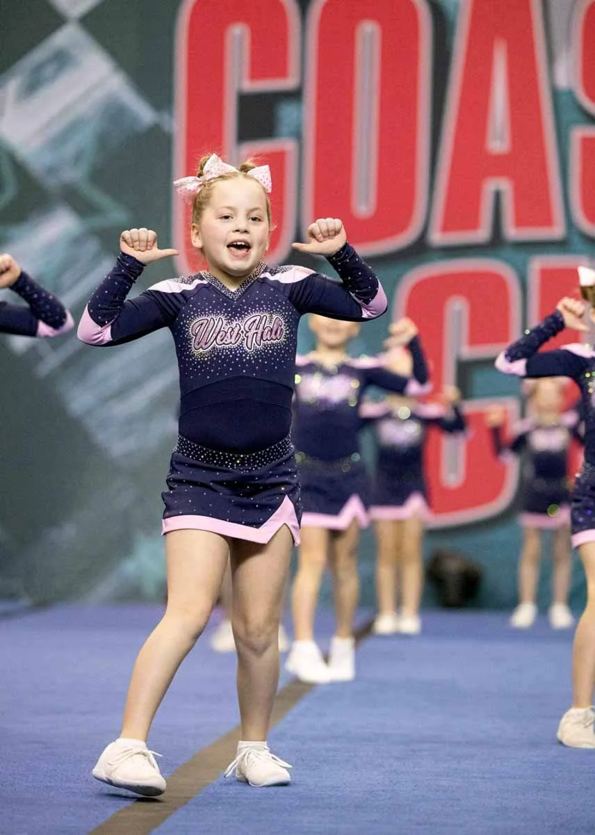 cheerleader poses with their thumbs pointing at themselves