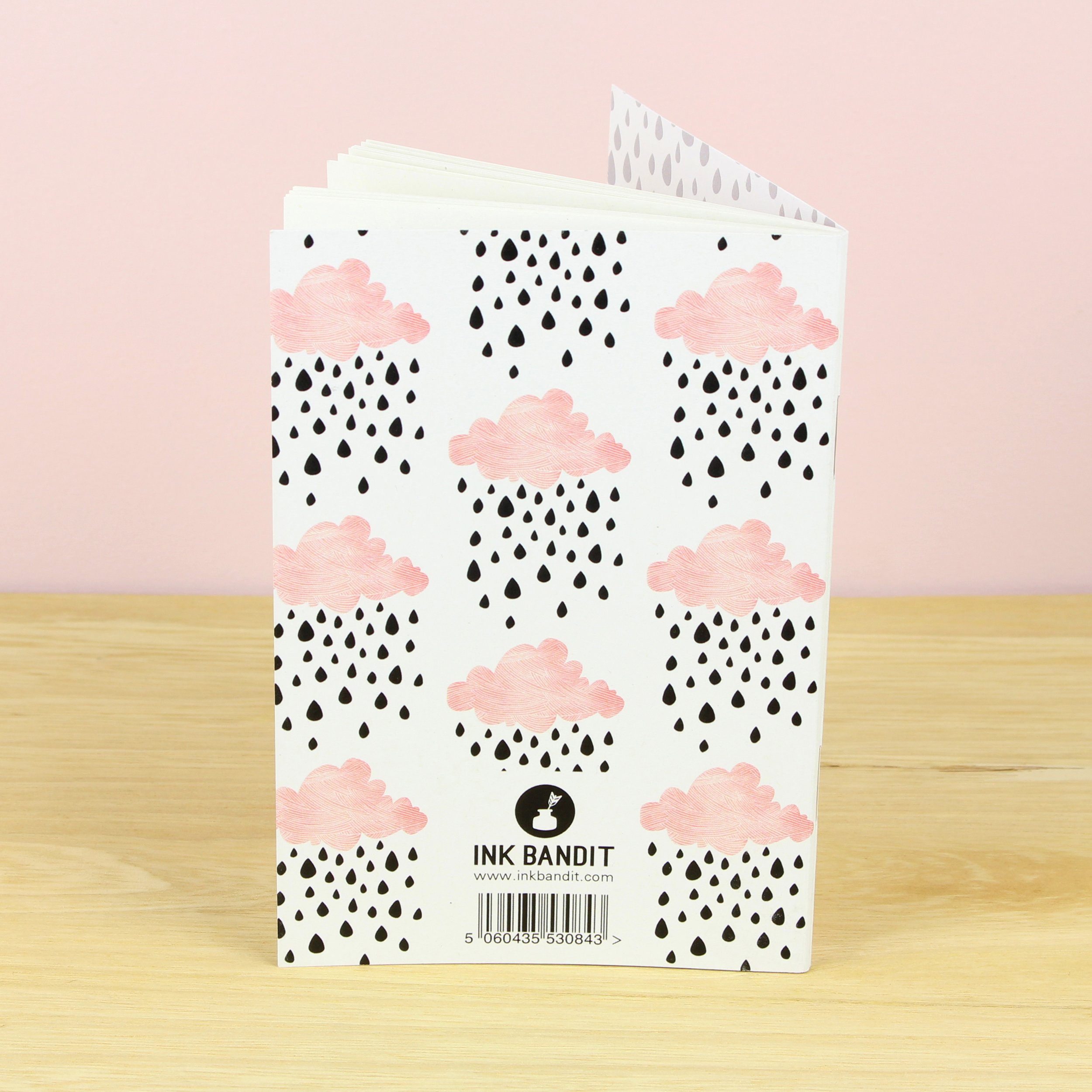 Reverse cover of Raining clouds A6 Notebook with illustration of pink clouds with black raindrops